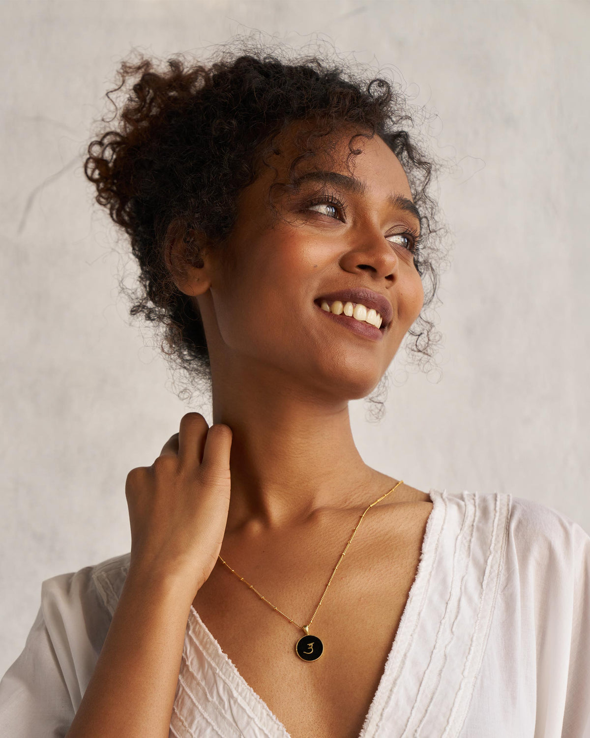 Person wearing a black and gold Alphabet U charm necklace.