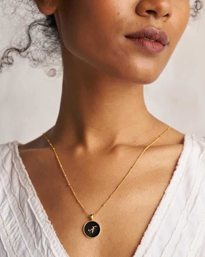 Black and gold Alphabet Z charm with a Devanagari letter worn on a satellite chain.