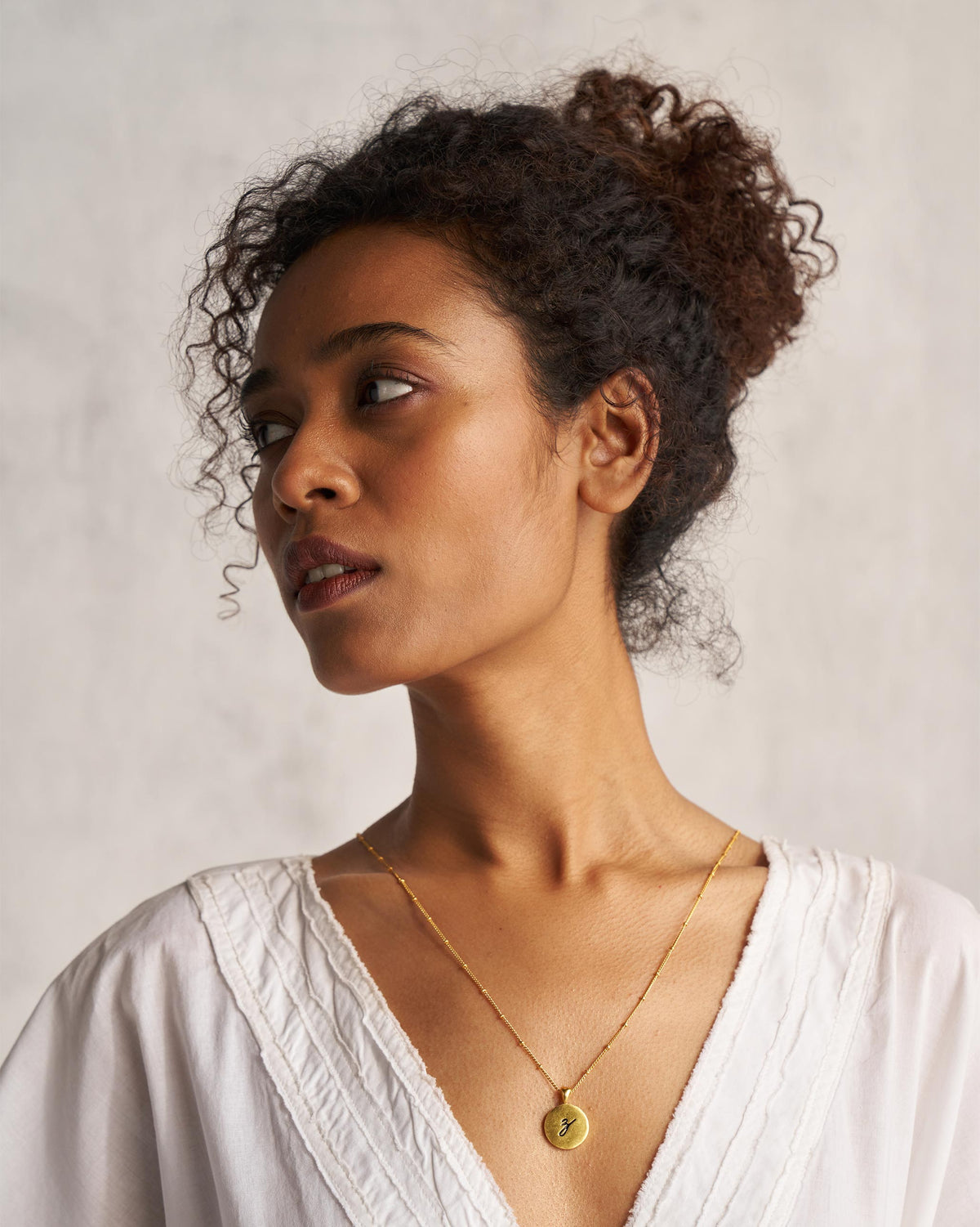Person wearing a gold Alphabet Z charm on a fine chain.