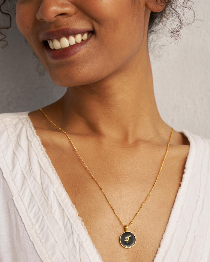 Black and gold Alphabet Y charm with य worn on a satellite chain.