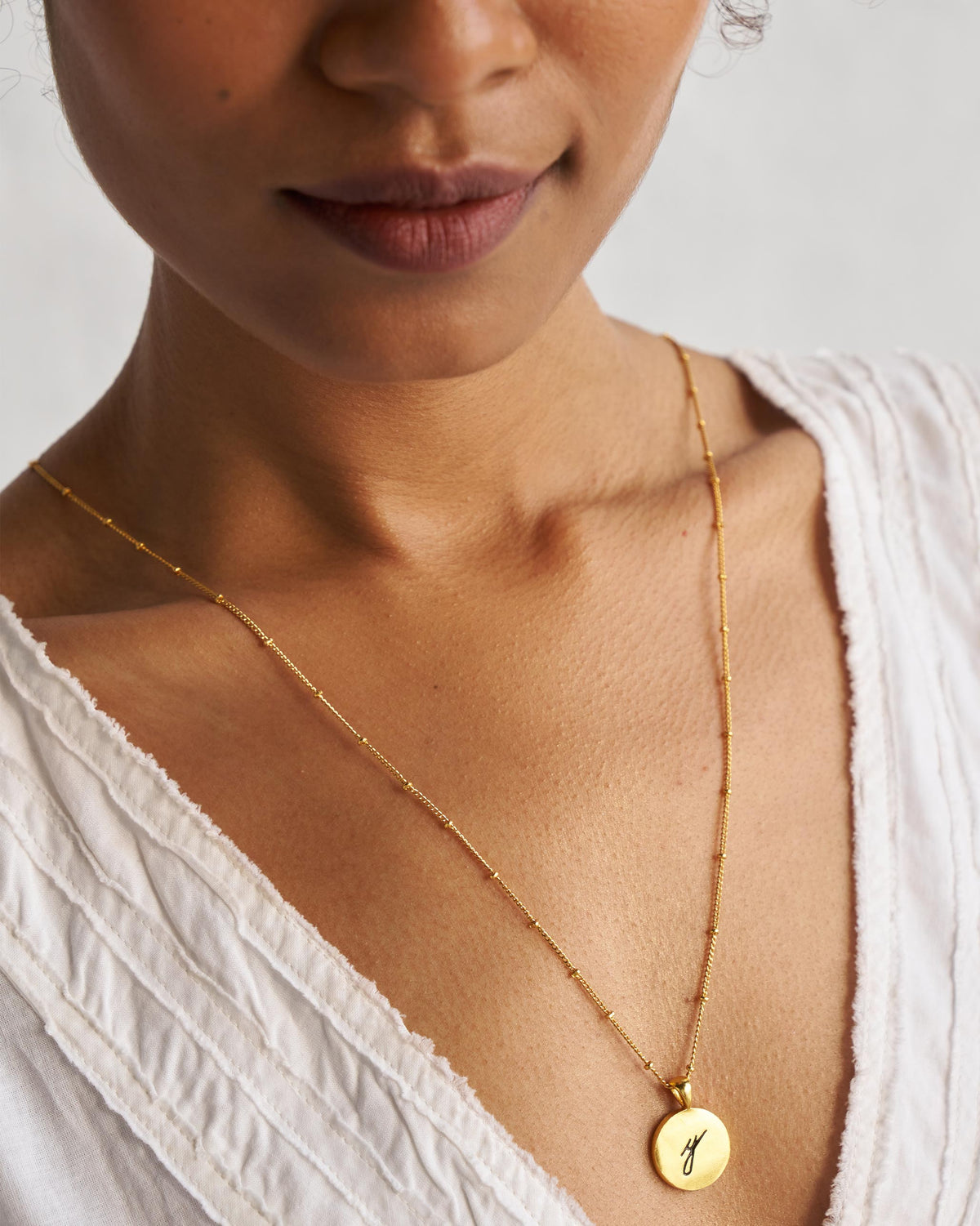 Gold Alphabet Y charm with a black script letter y when worn.