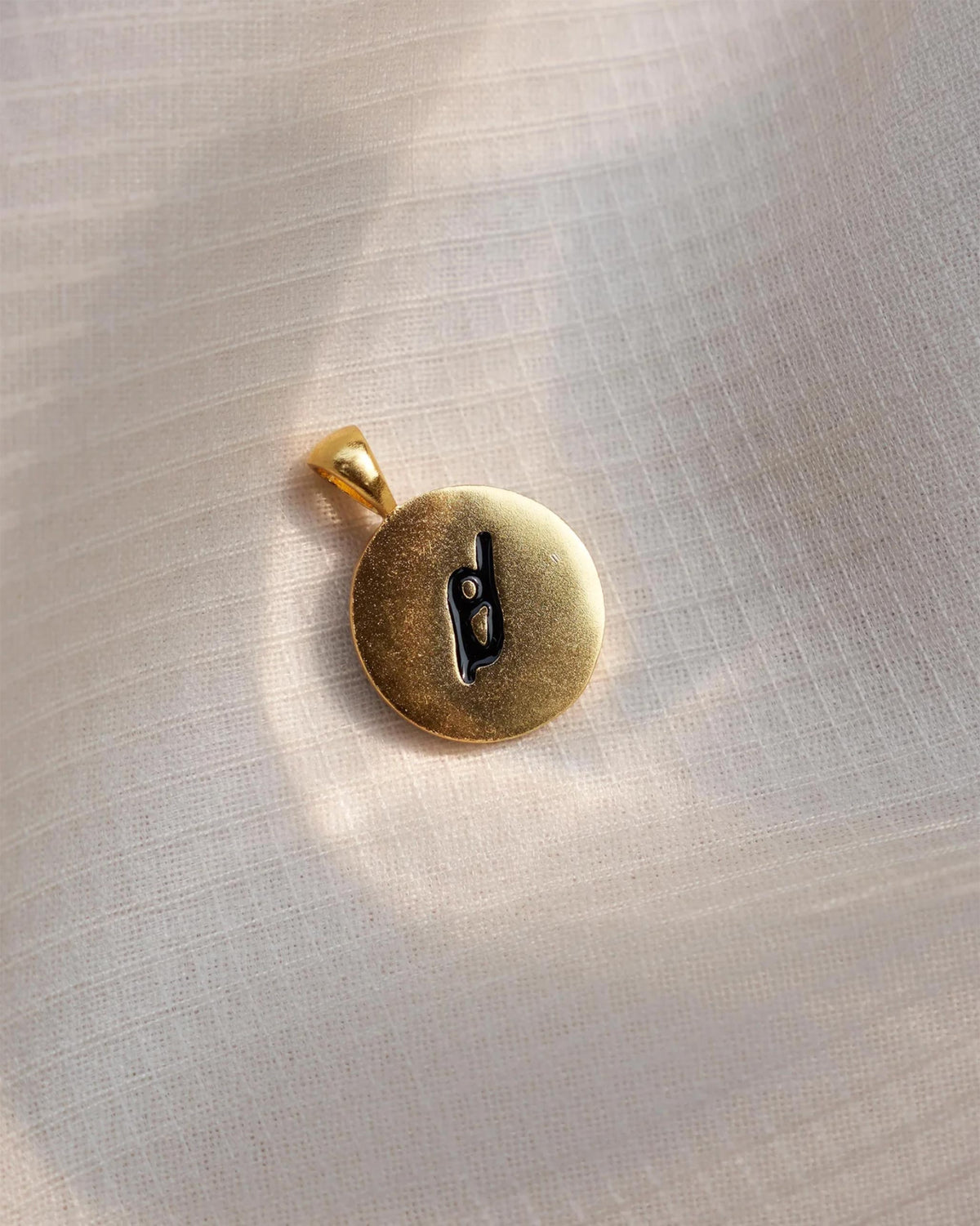 Close-up of a gold Alphabet O charm with a black script o.