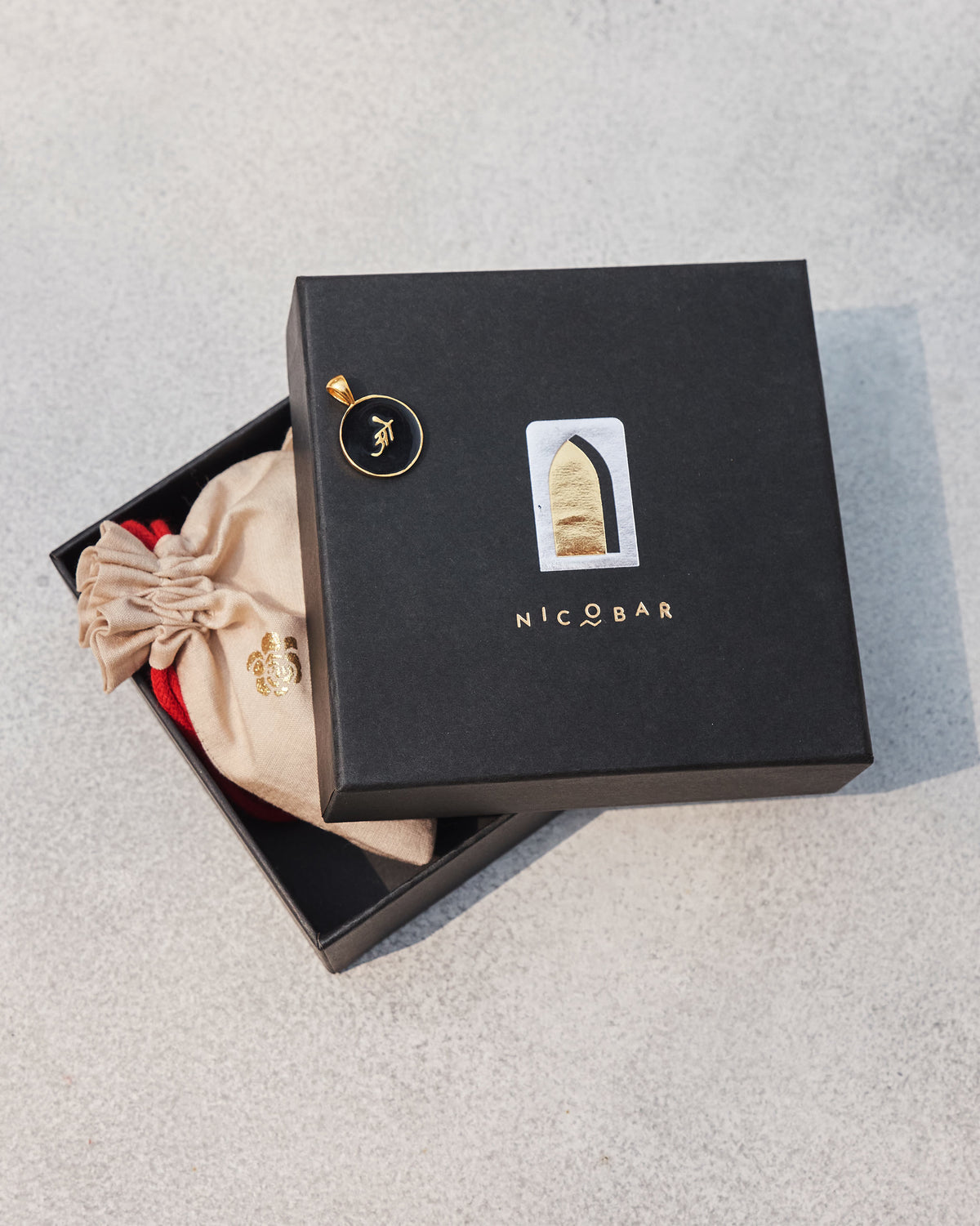 Black and gold Alphabet O charm on a Nicobar gift box.
