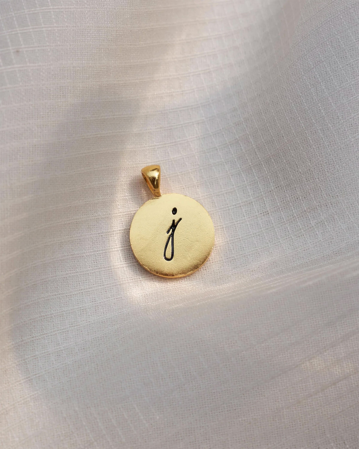 Close-up of a gold Alphabet J charm with a black script j.