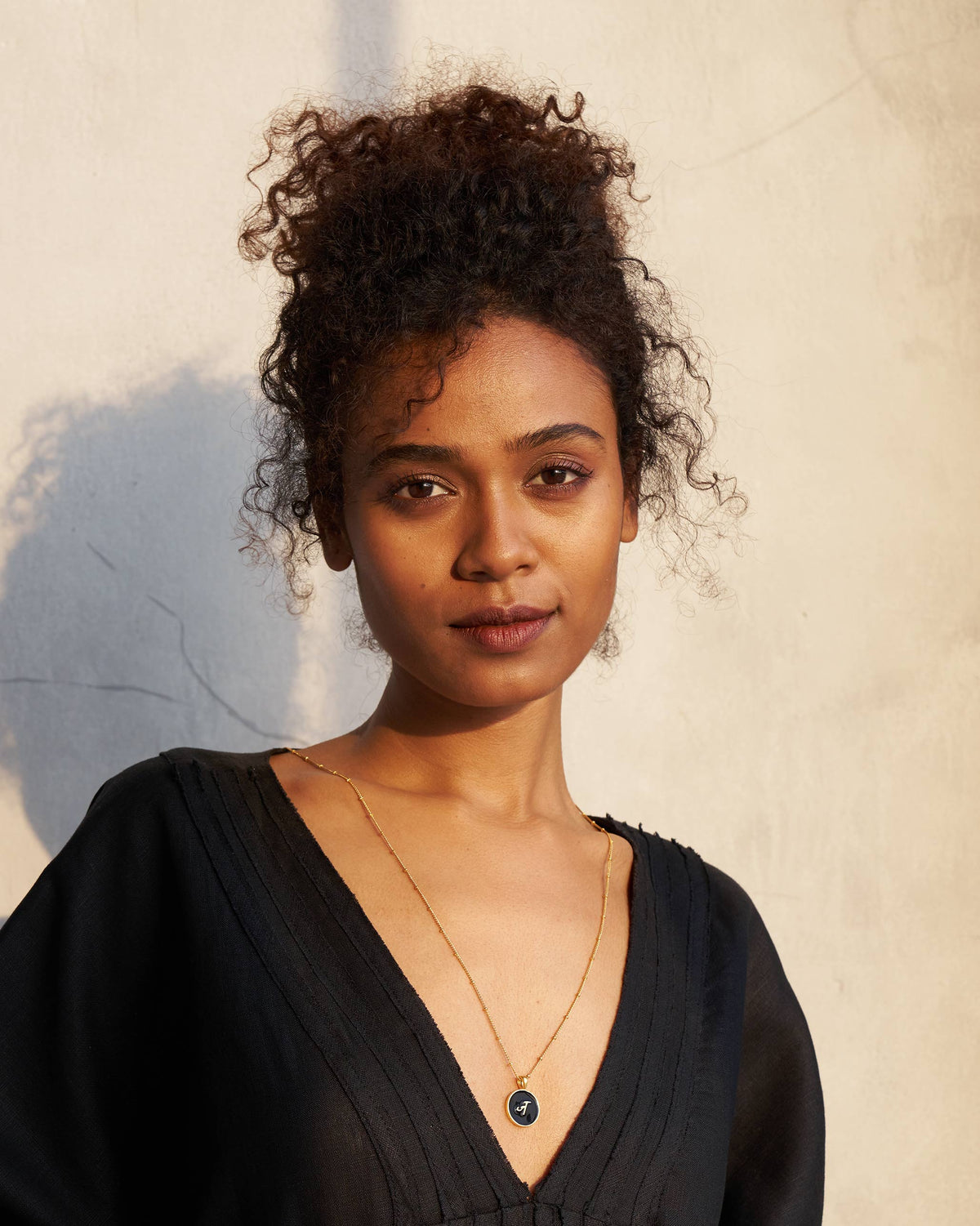 Person wearing a black and gold Alphabet J charm necklace.