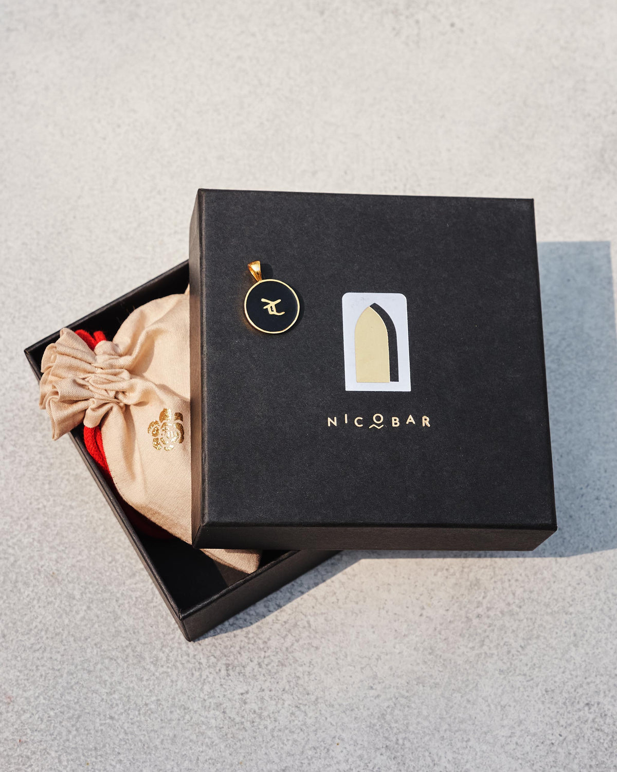 Black and gold alphabet charm on a Nicobar gift box.