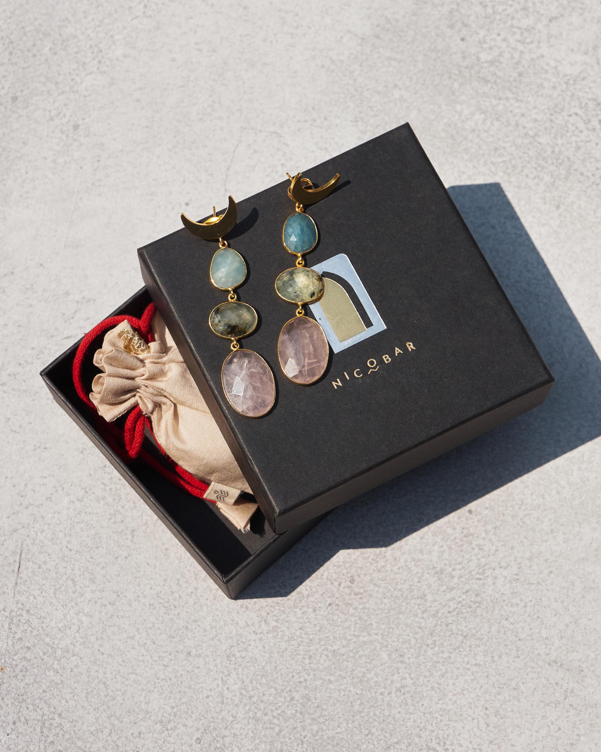 Rosy Moon Earrings in a Nicobar gift box beside a drawstring pouch.