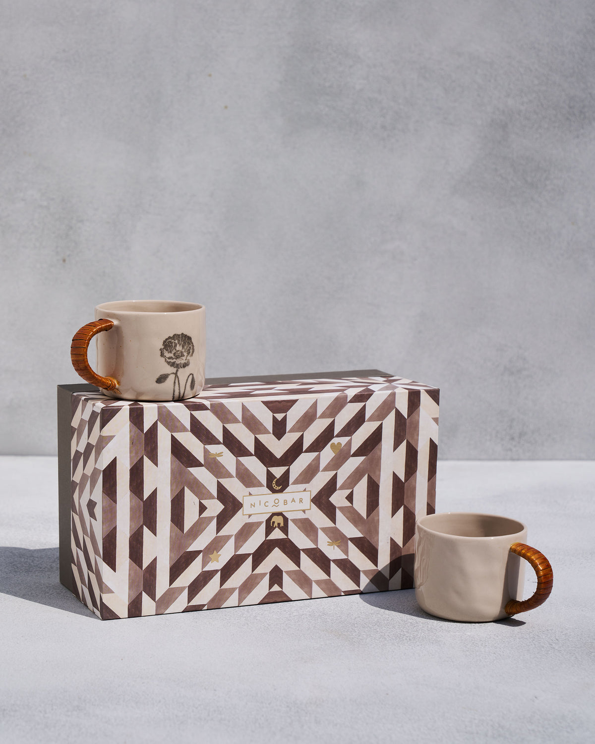 Poppy mug set of two with rattan handles and a geometric Nicobar gift box.
