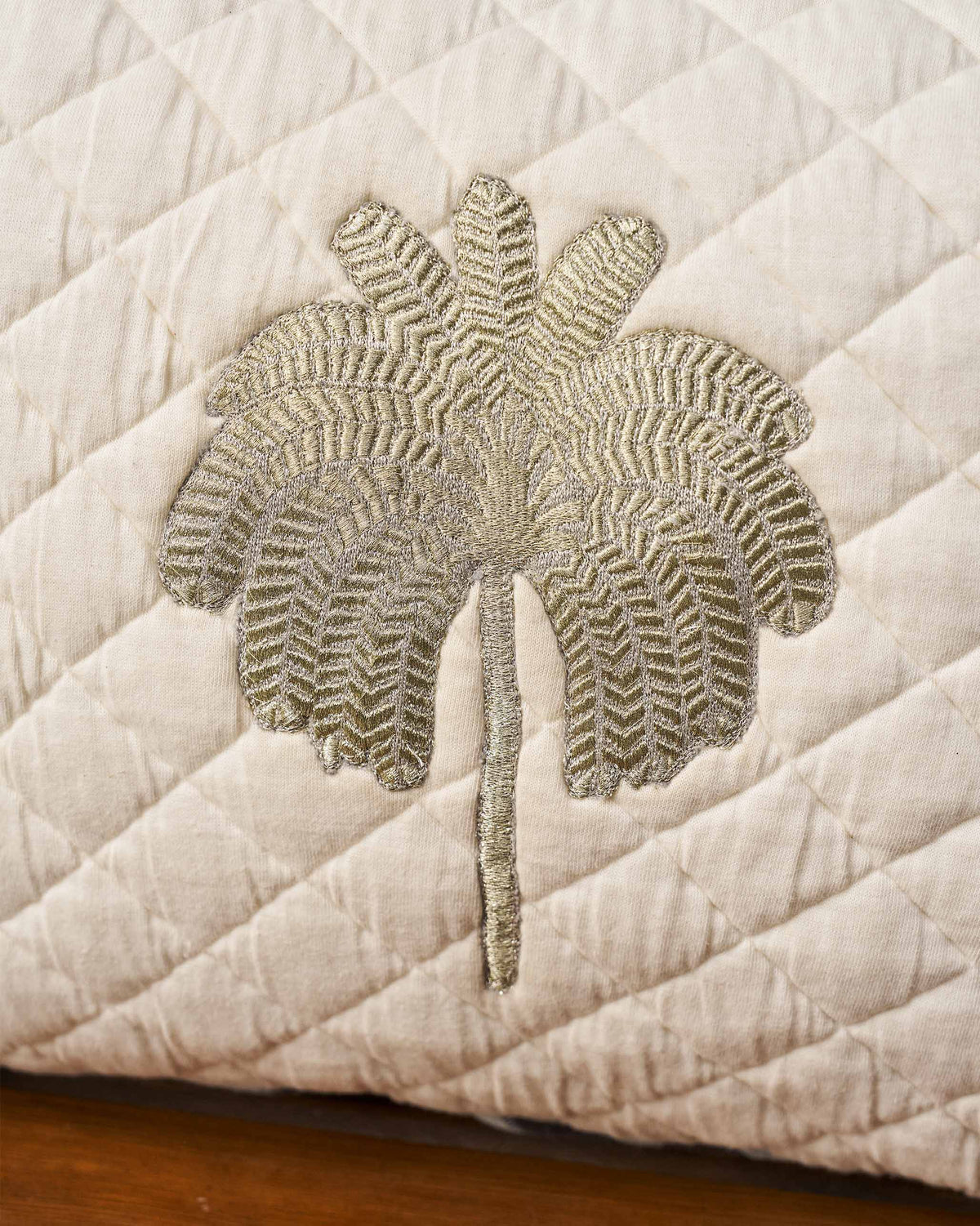 Close-up of the embroidered palm motif on the Quilted Palm cushion.