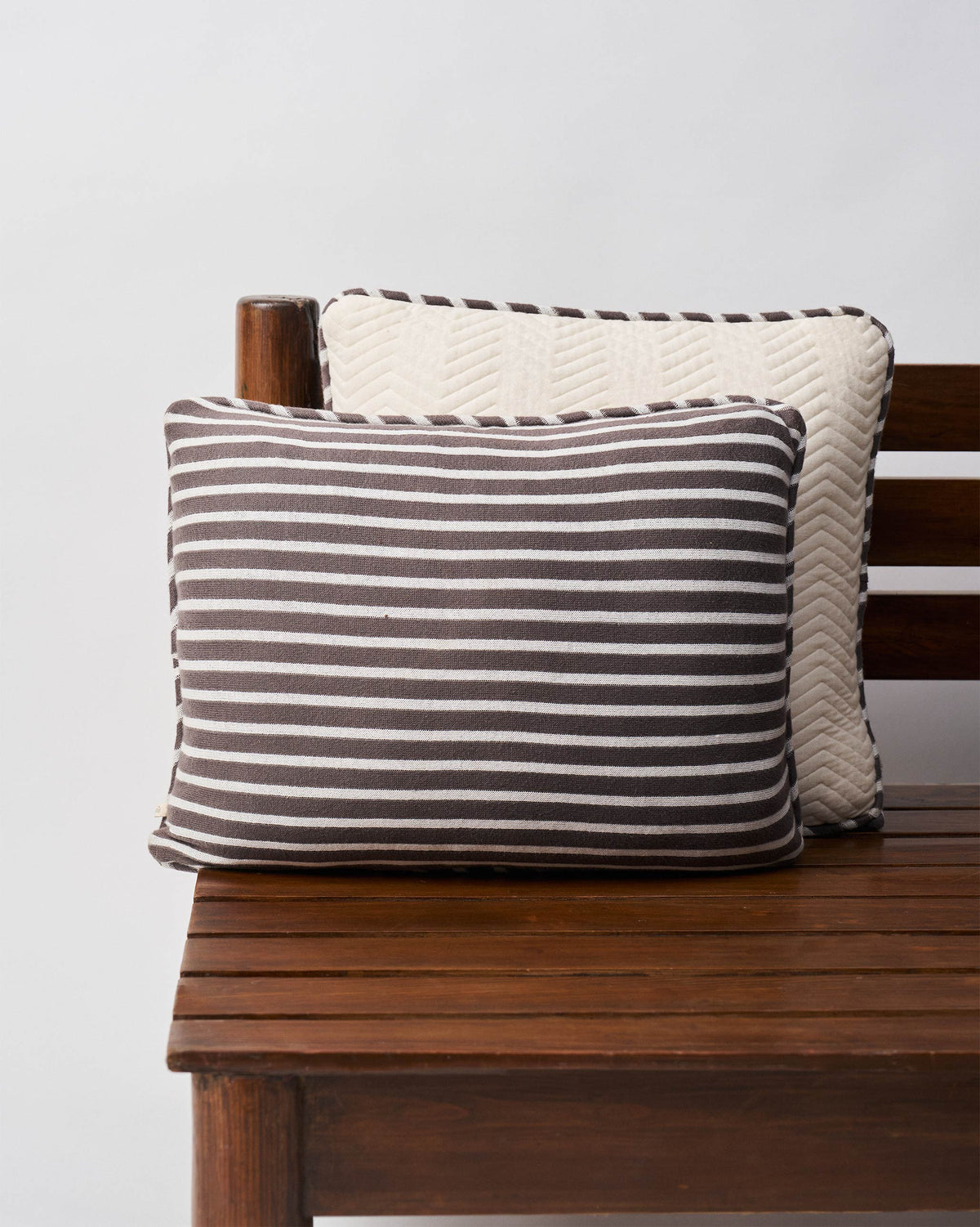 Quilted Dragonfly Cushion Cover in brown and cream stripes, shown on a bench.