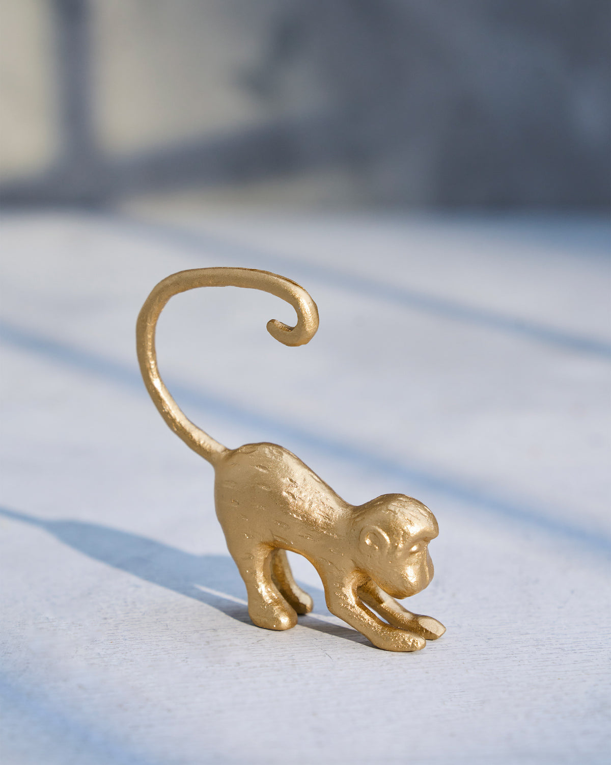 Side view of a gold monkey menu card holder with its tail curled.