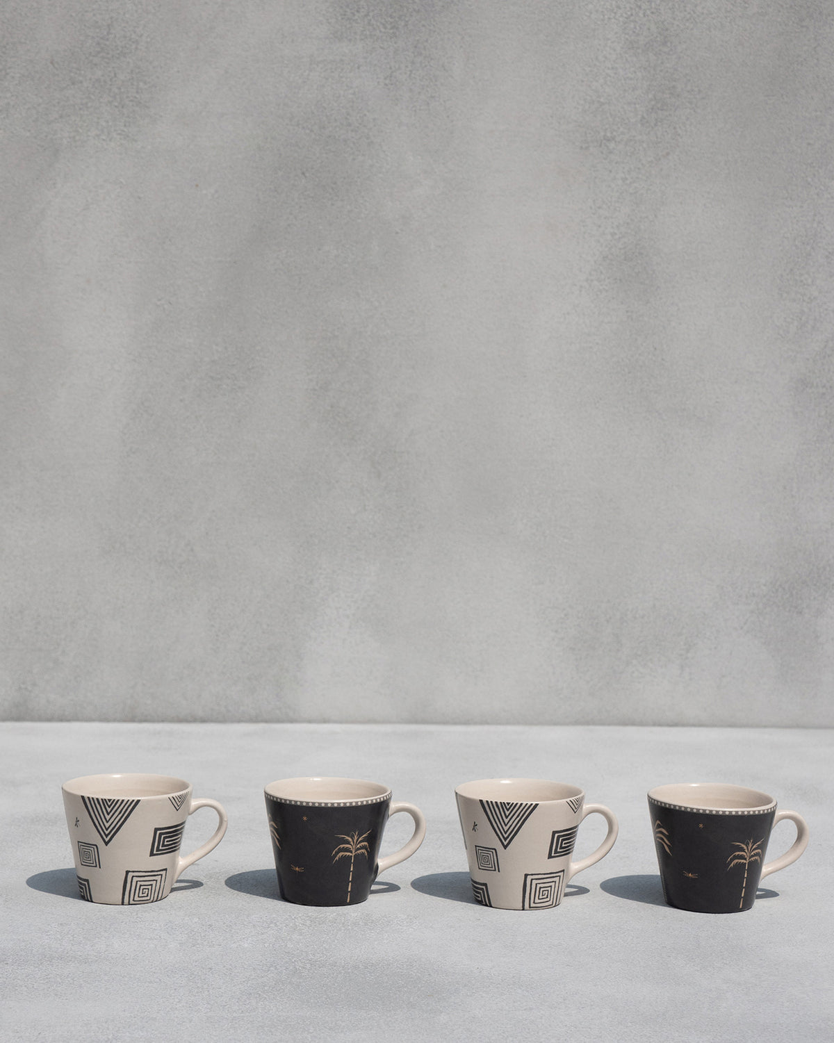 Four Serenity espresso mugs alternating geometric and palm tree prints.