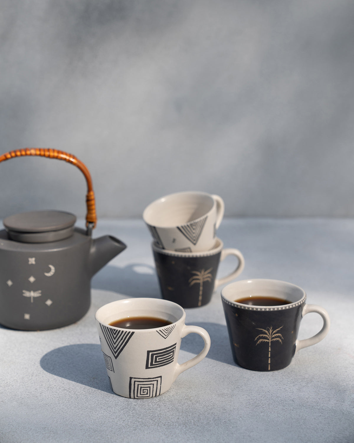 Serenity espresso mugs with coffee beside a matching teapot.