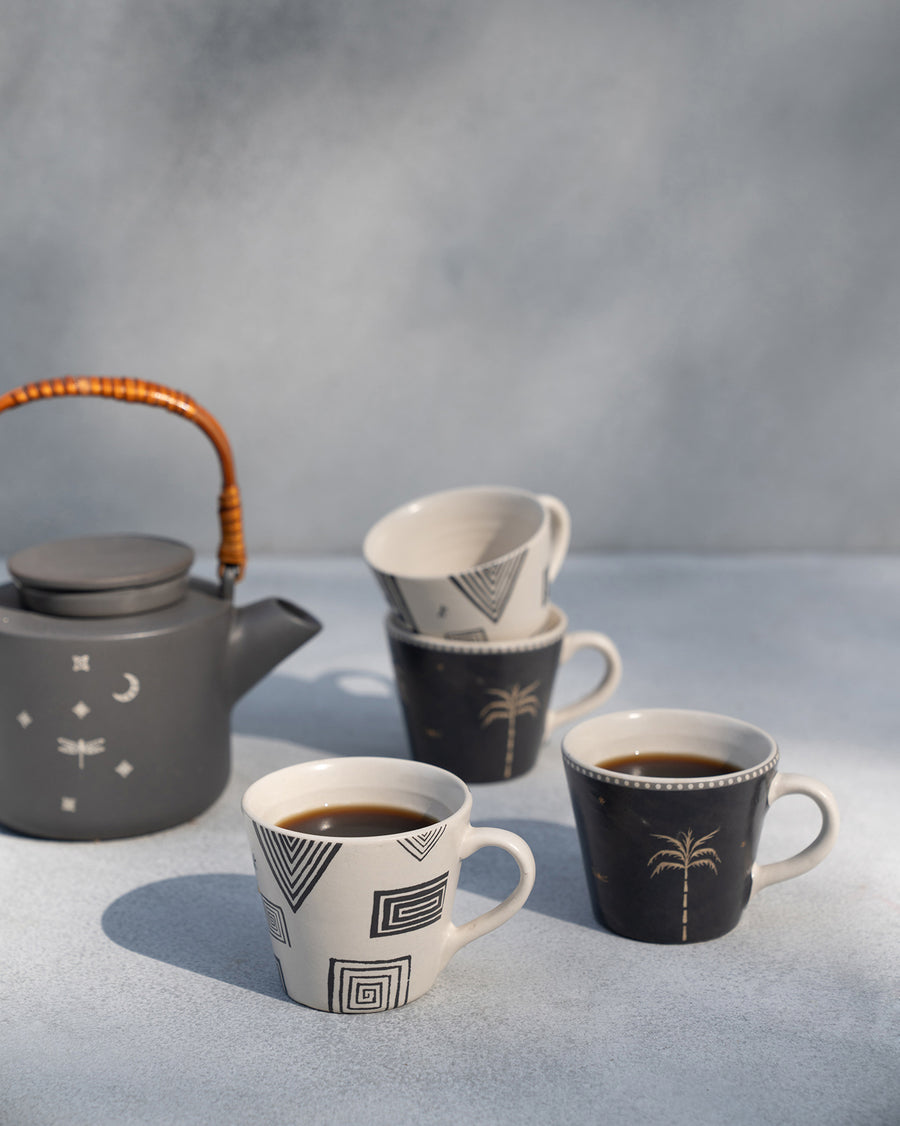 Serenity mugs with coffee beside a grey teapot with a cane handle