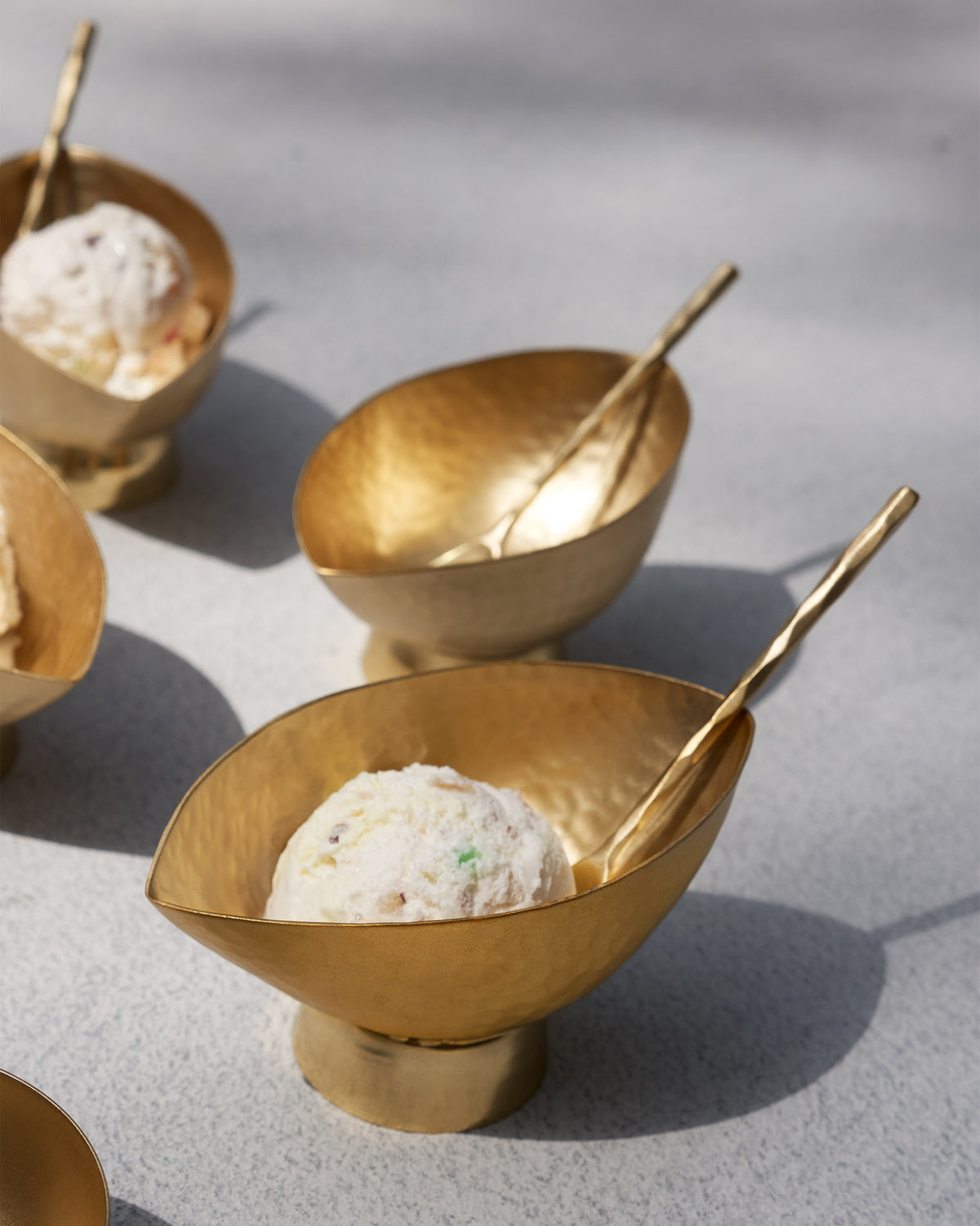 Chakra Gelato Cups filled with ice cream and matching brass spoons.
