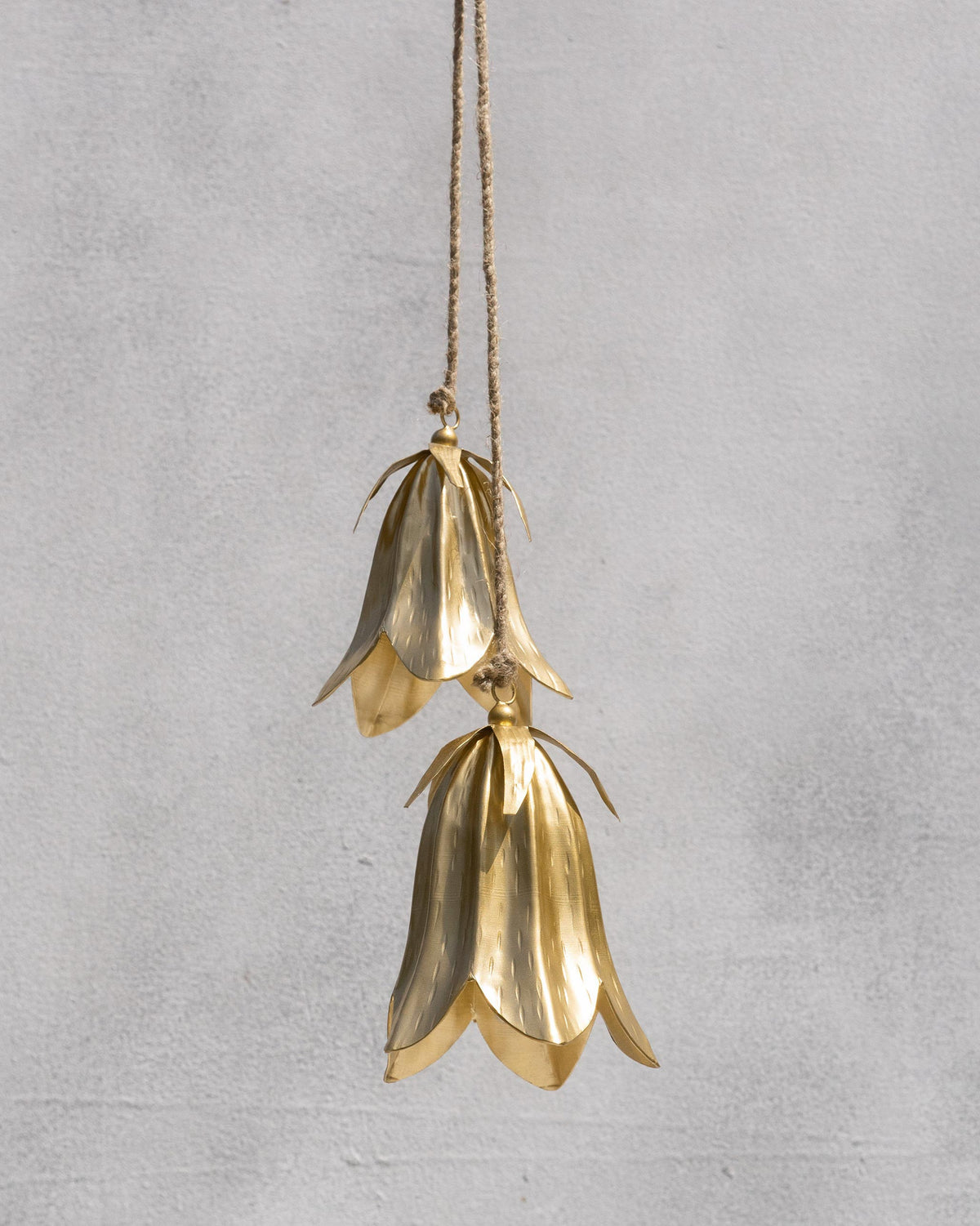 Pair of gold flower-shaped Botanical Bells hanging on jute rope.