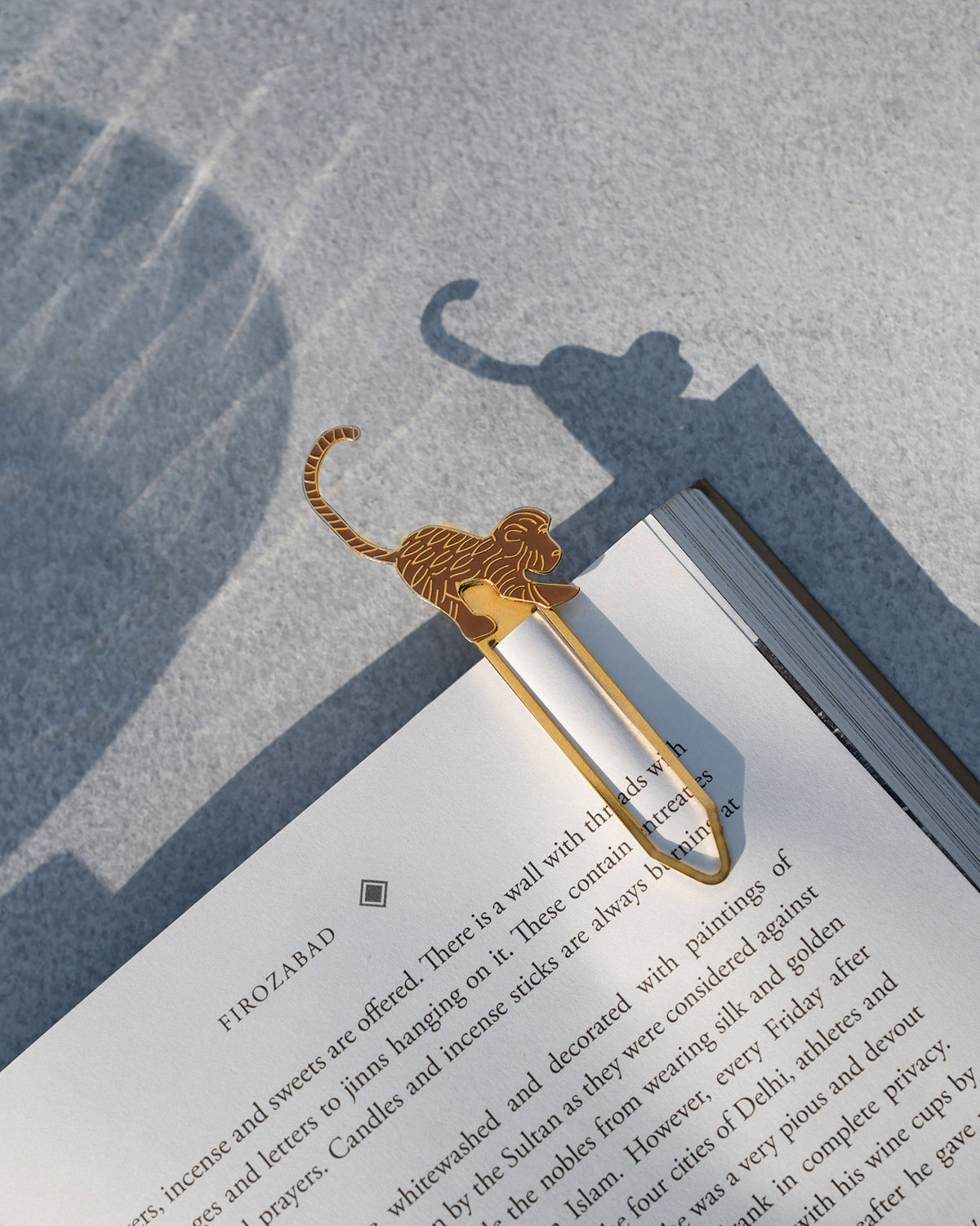 Gold safari monkey bookmark clipped to an open book.