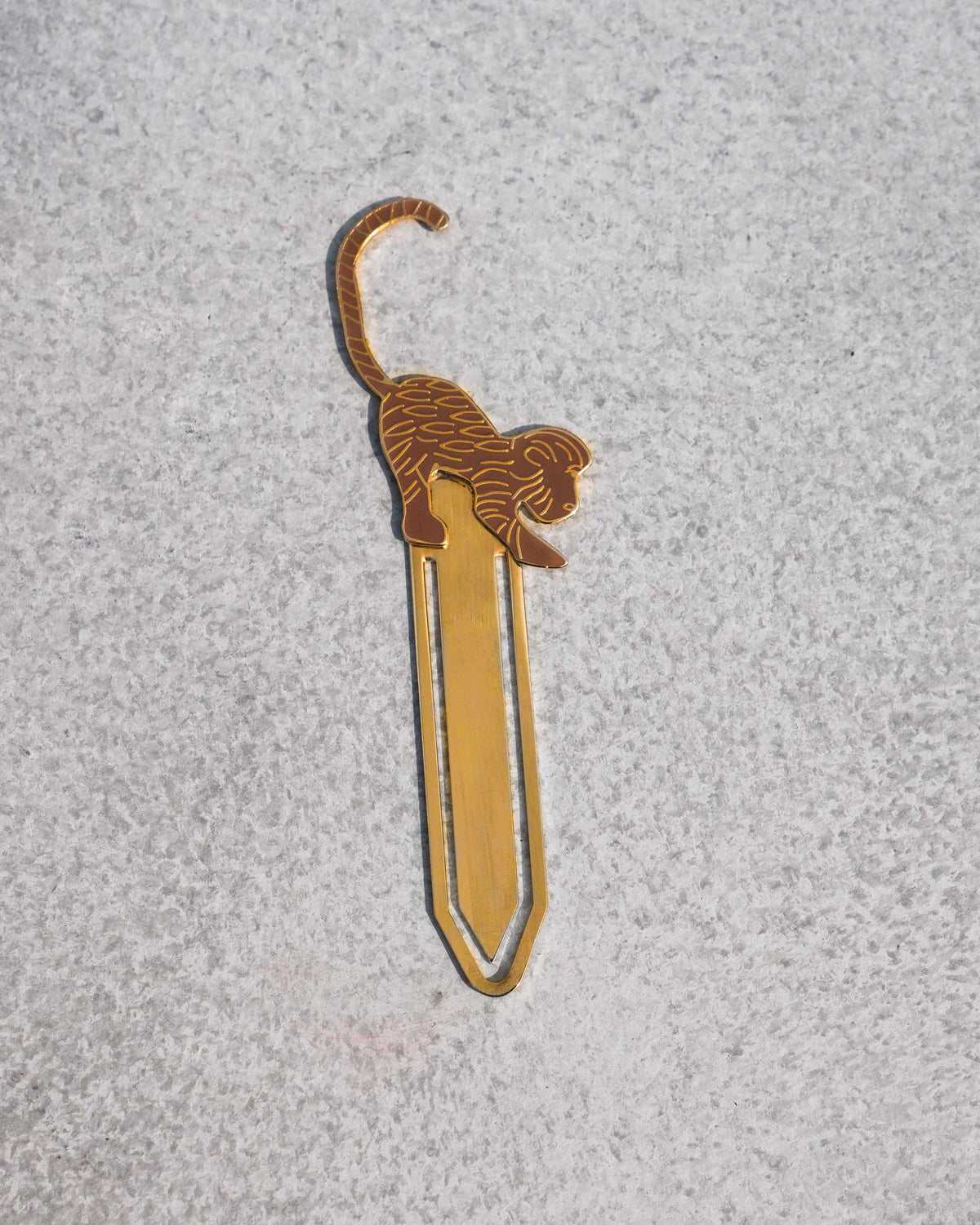Gold safari monkey bookmark on a grey surface.