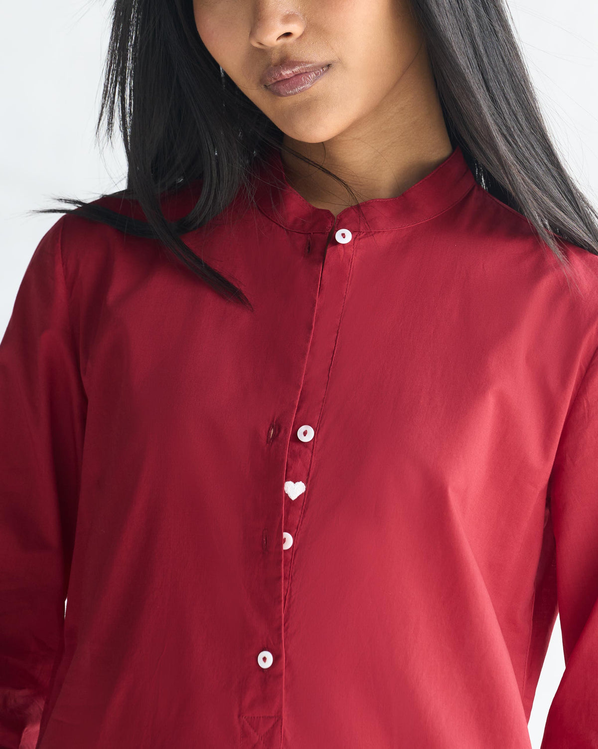 Close-up of a red long kurta showing the mandarin collar and heart button.