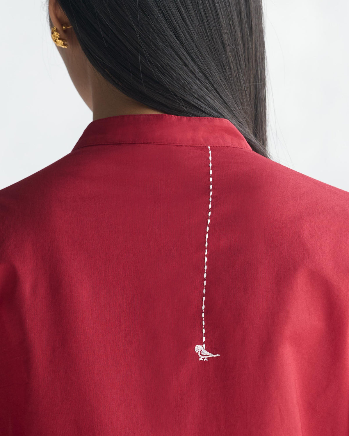 Close-up of the back of a red long kurta with a white bird motif.