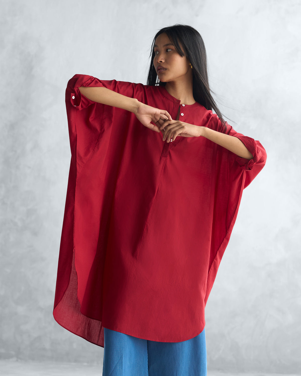 Person wearing a red Lazy Sunday tunic with wide sleeves and side slits.