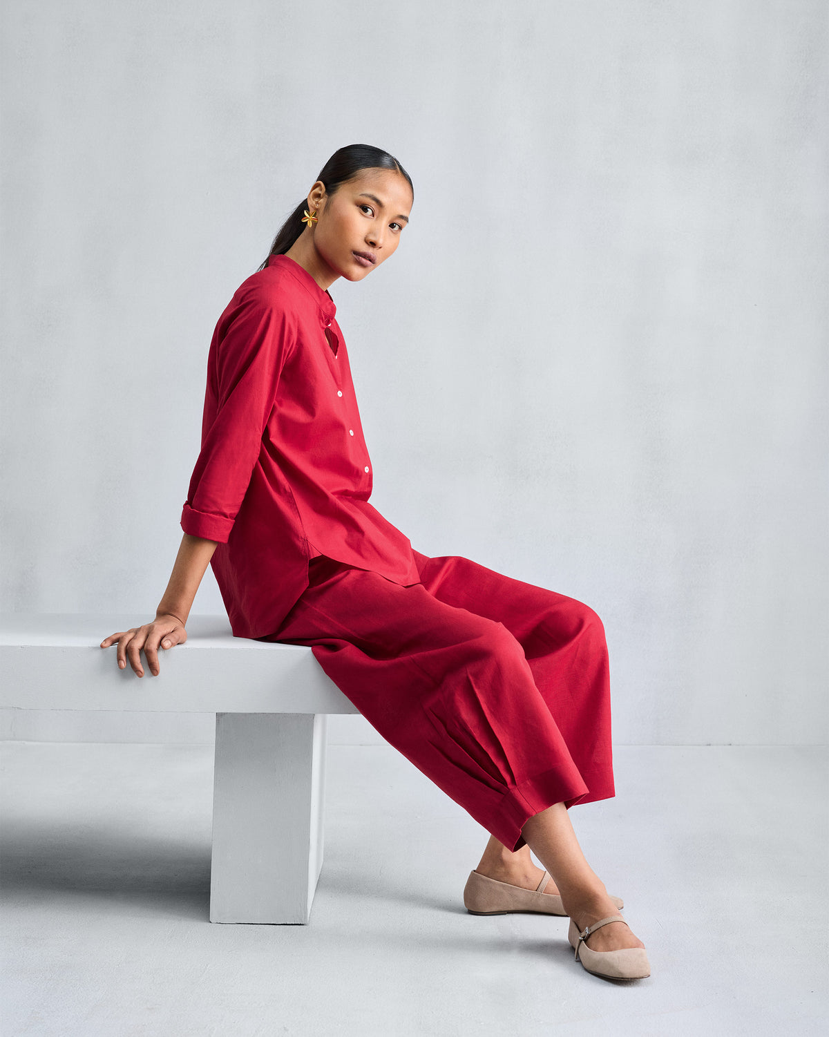 Person wearing a red mandarin collar set with matching wide pants.