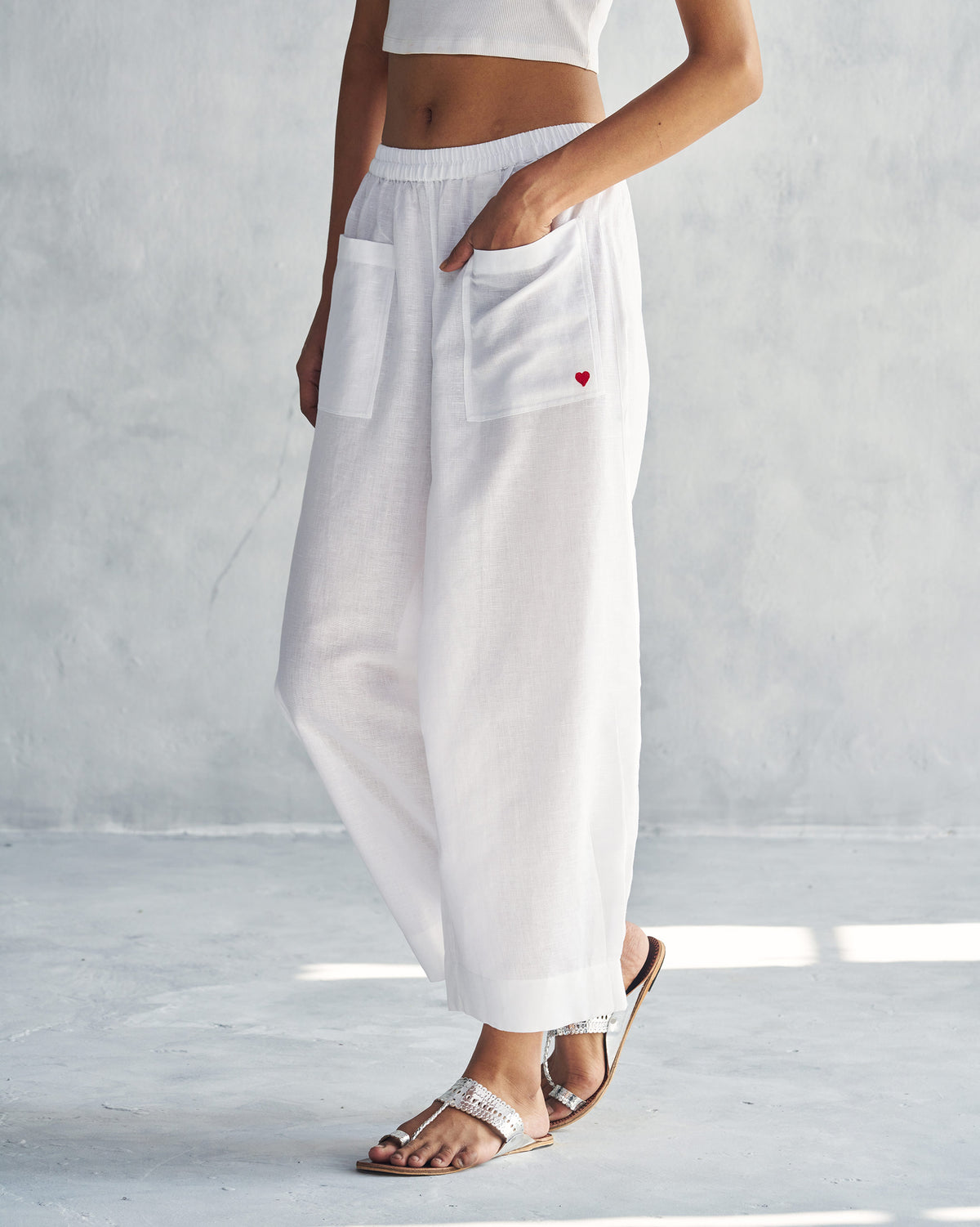 Side view of white Serene pants with a hand in the patch pocket.