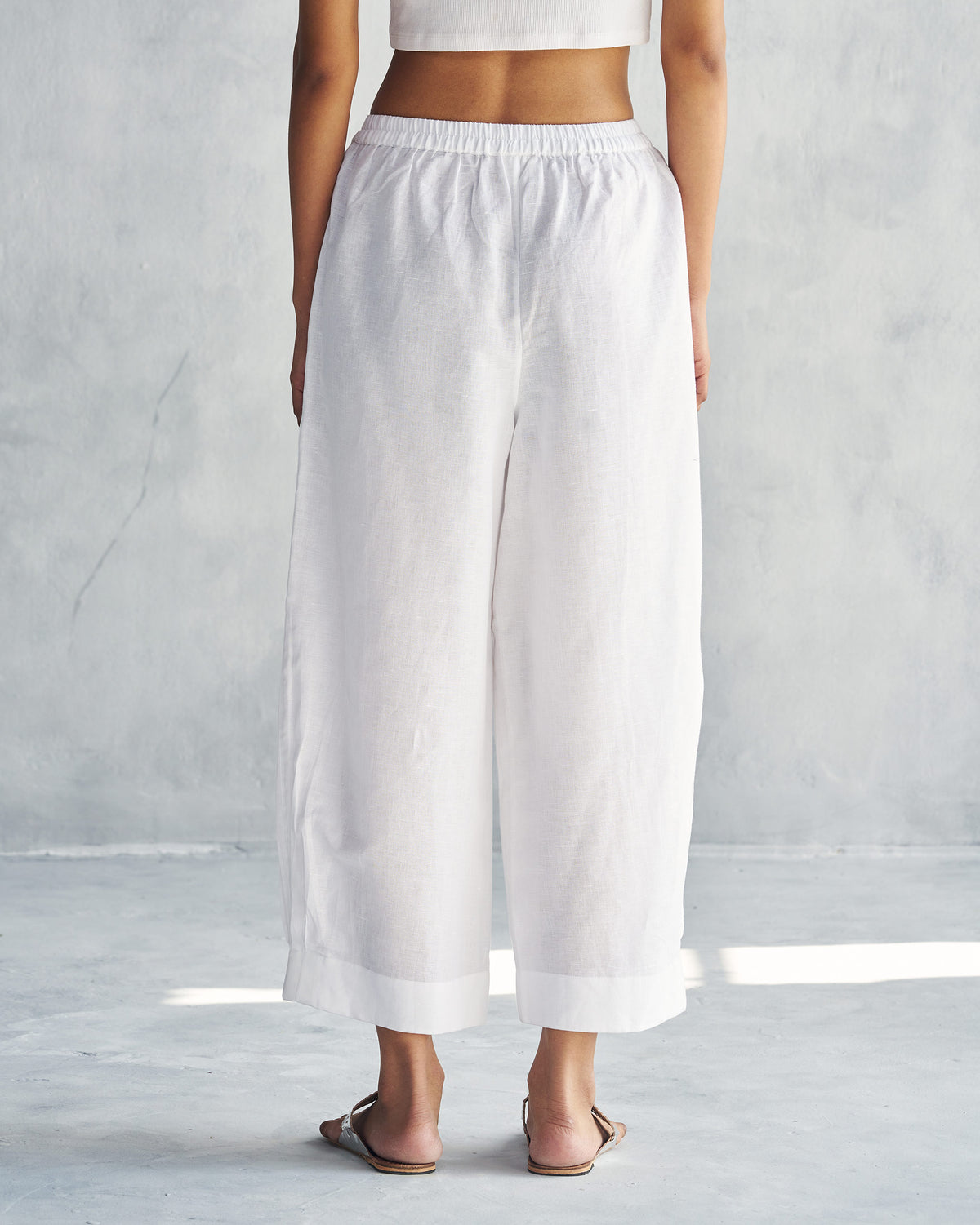 Back of white Serene pants with an elastic waistband and cropped wide legs.