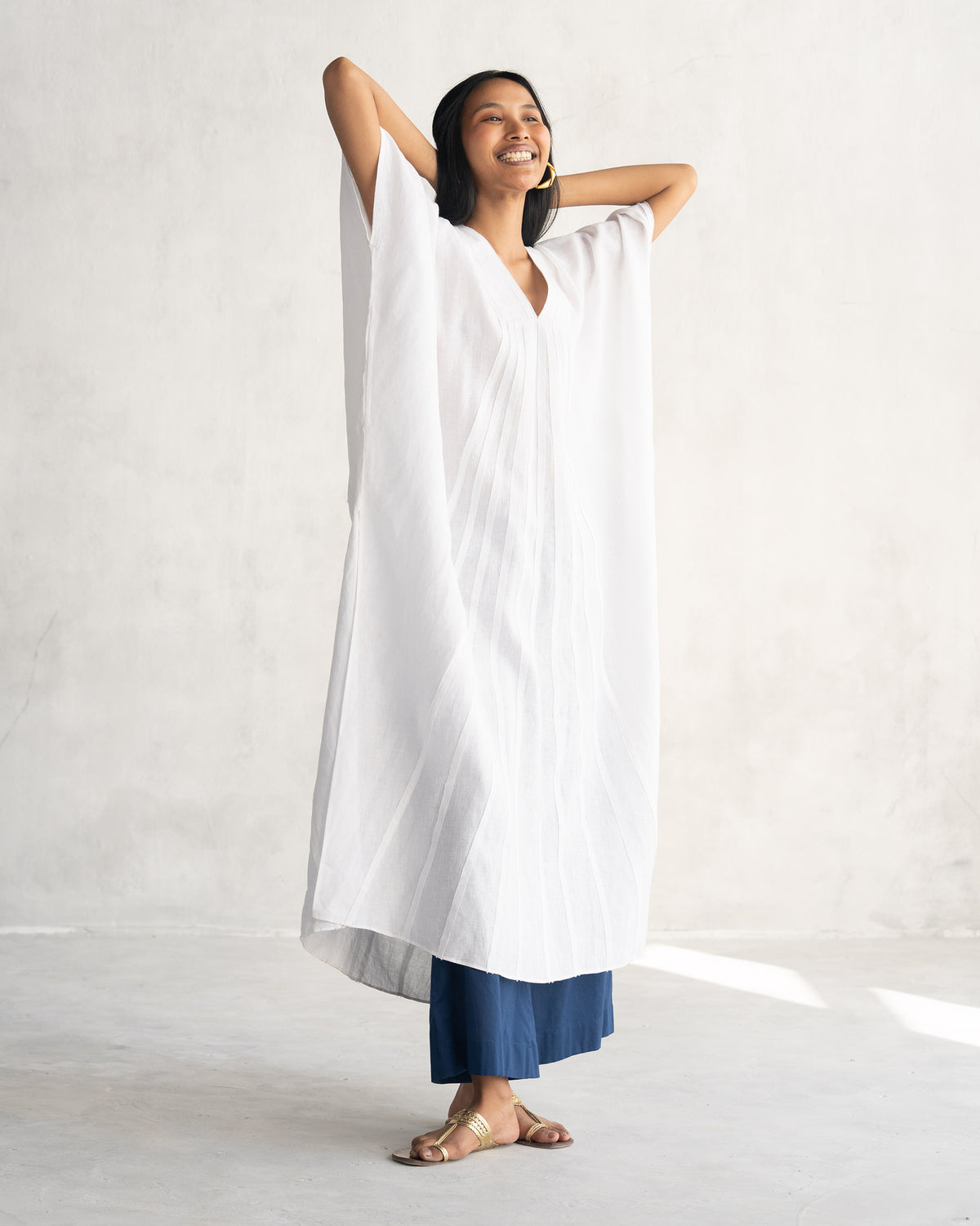 Person wearing a white Tulum kaftan with wide short sleeves.