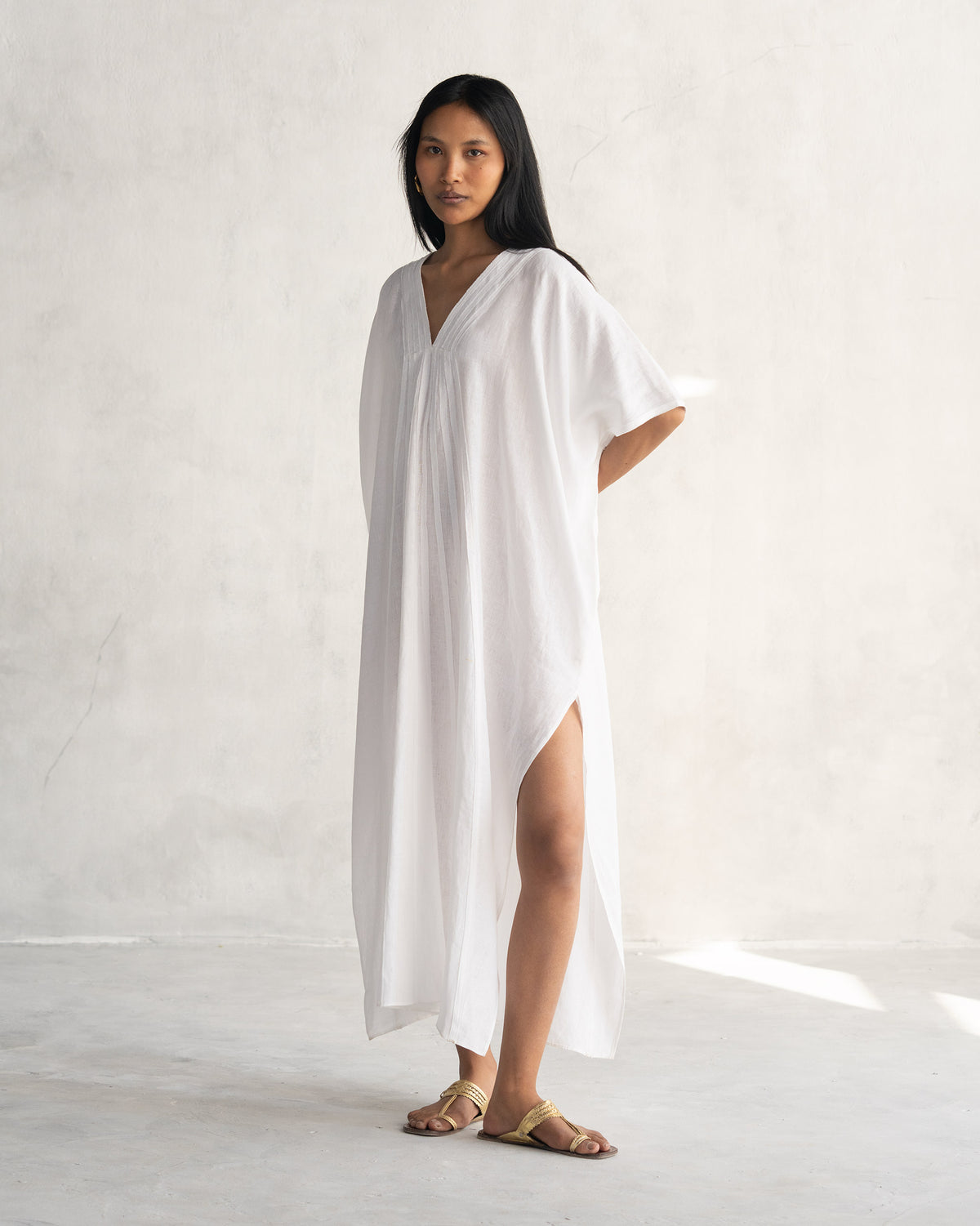 Side view of a white Tulum kaftan showing a high side slit.