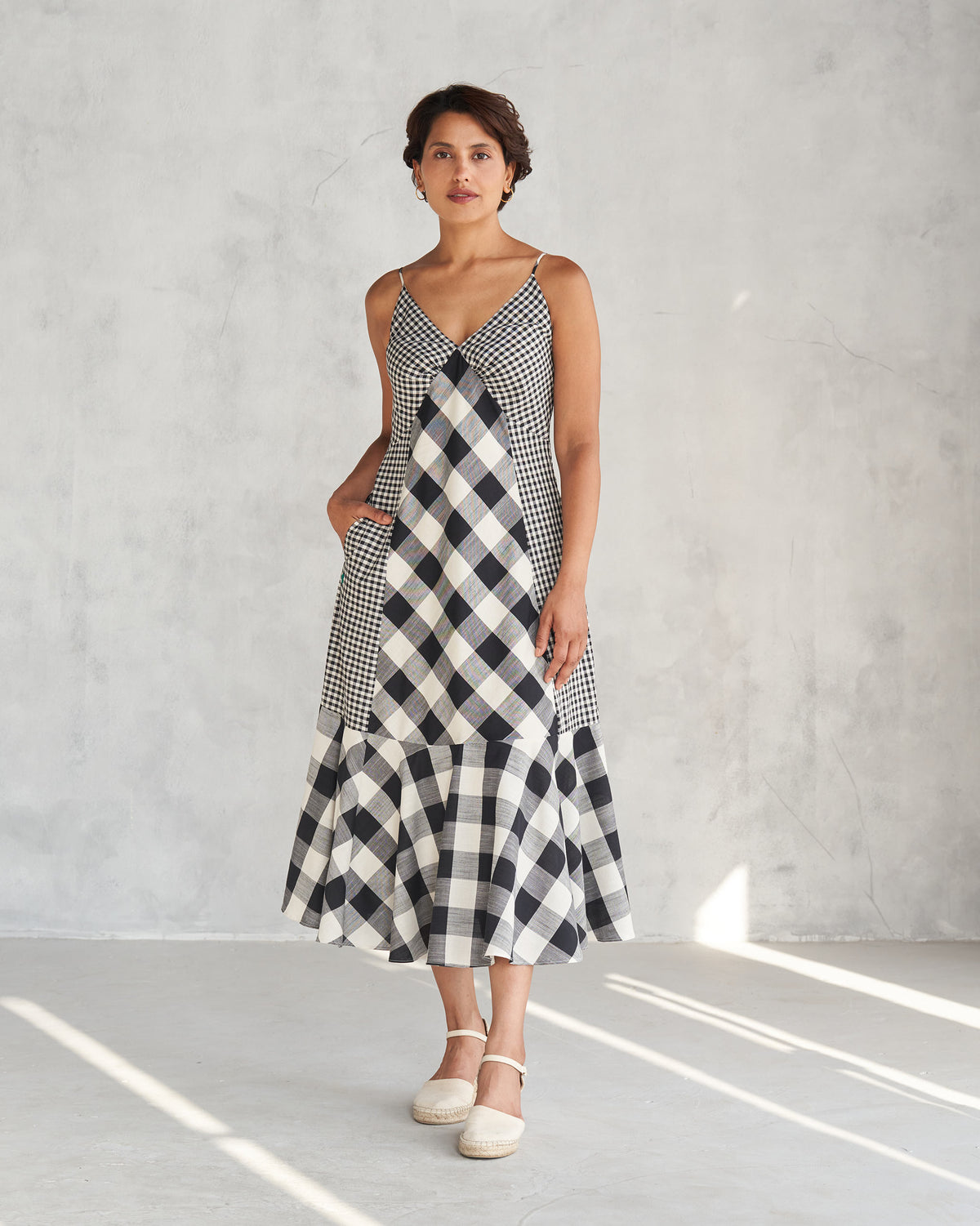 Person wearing an ivory and black check strappy tiered midi dress.