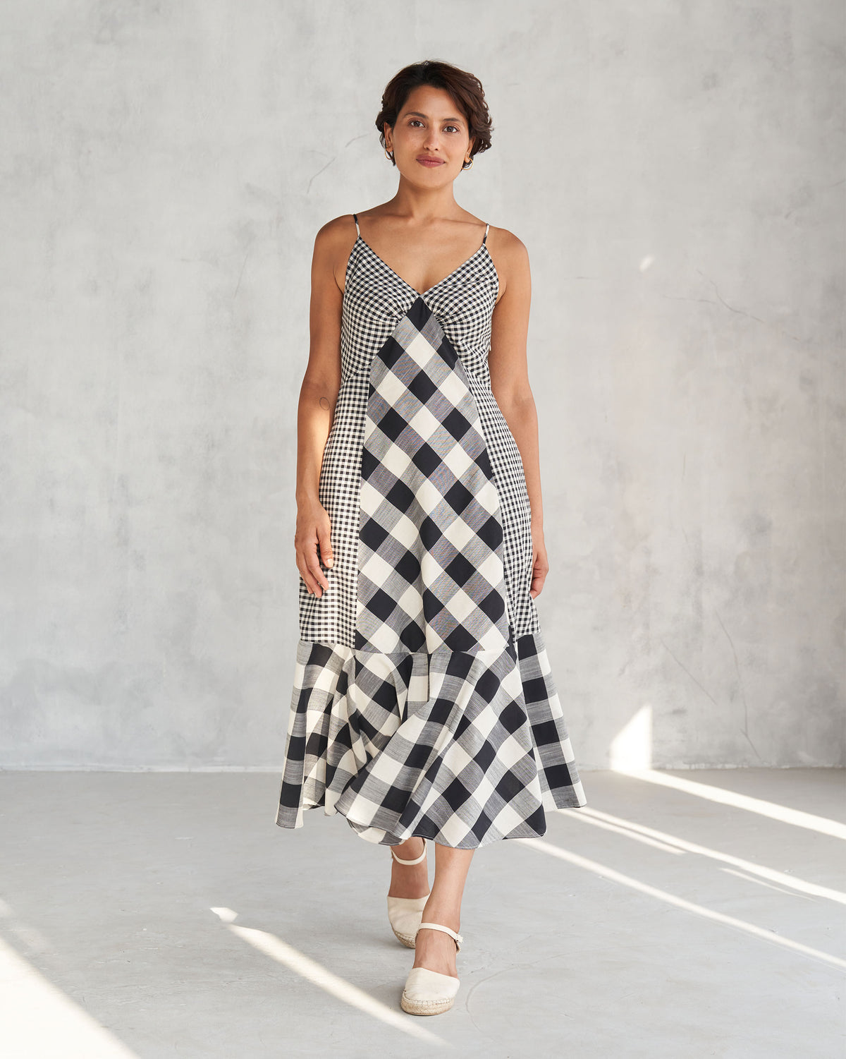 Person wearing an ivory and black check strappy dress with a diagonal panel.