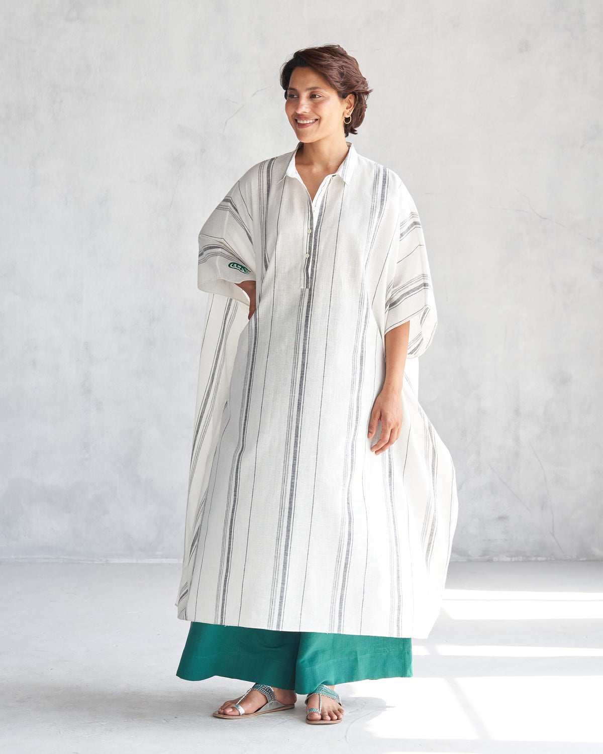 Person wearing an ivory collared kaftan with grey vertical stripes.