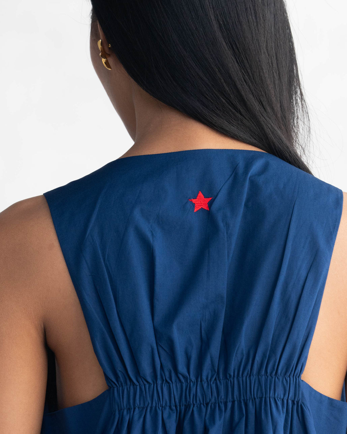 Close-up of a navy racerback dress showing a small red star embroidery.