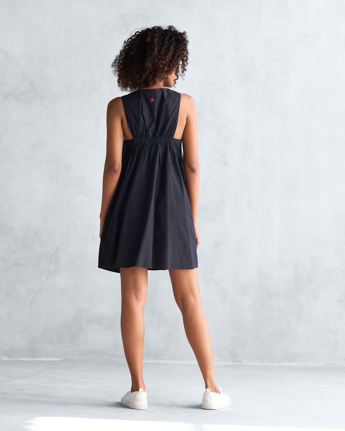 Back of a black short racerback dress worn by a person.