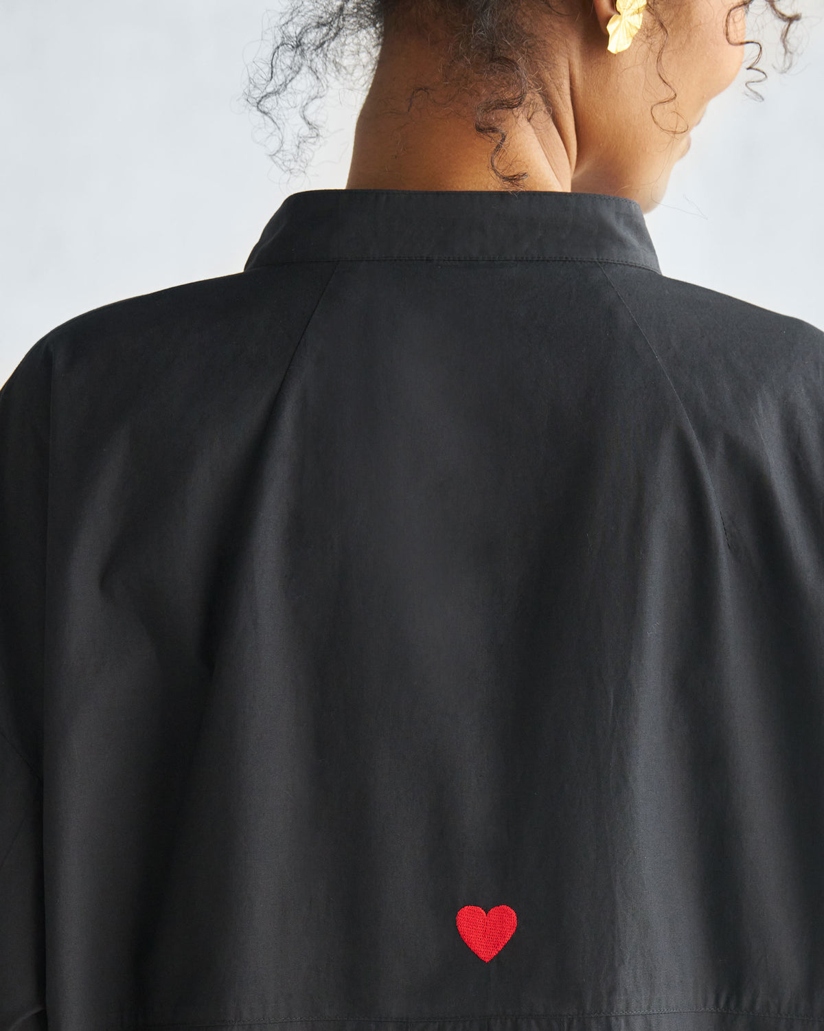Close-up of a black Cirrus shirt back showing a red heart embroidery.