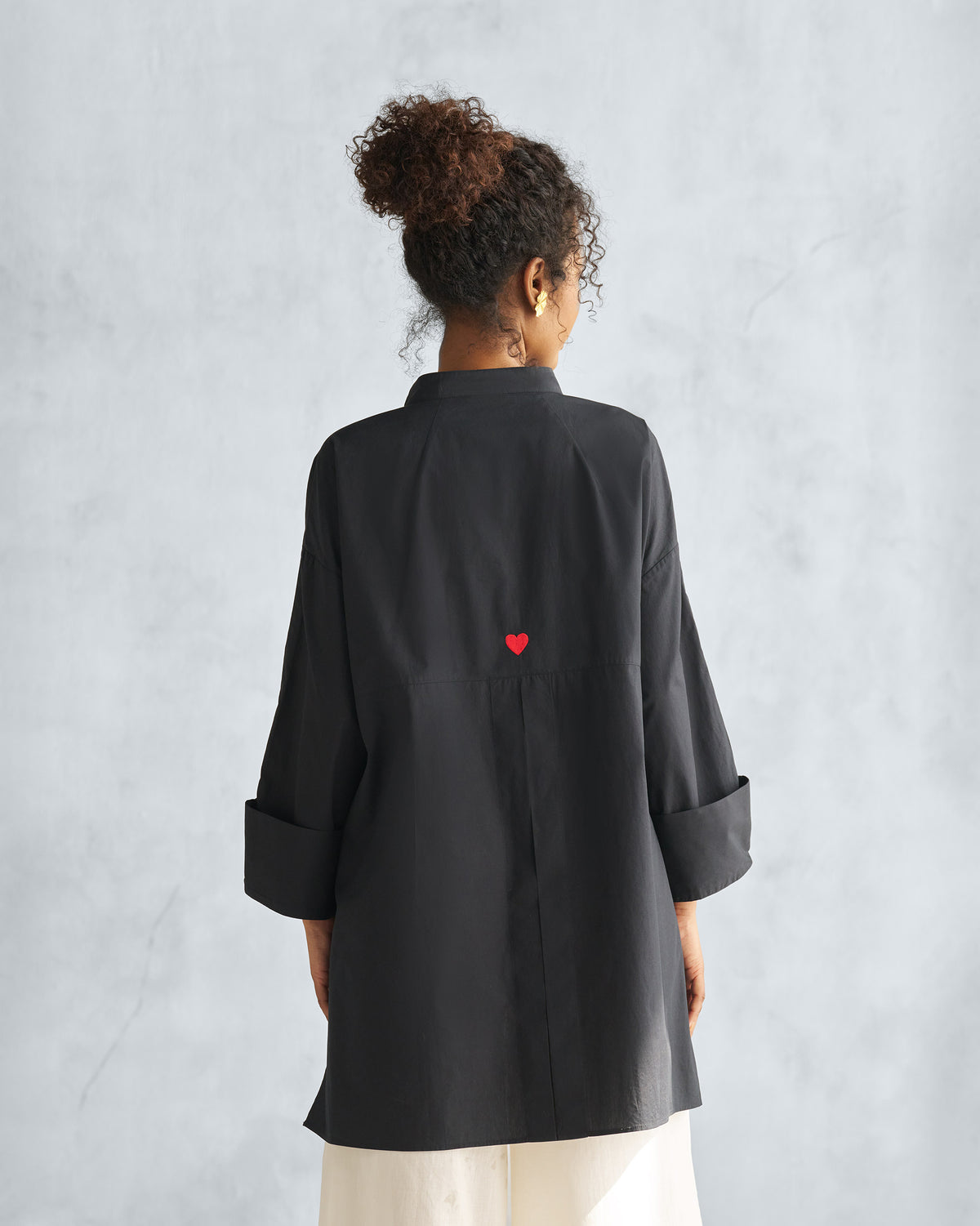 Back of a black Cirrus shirt with red heart embroidery and a box pleat.