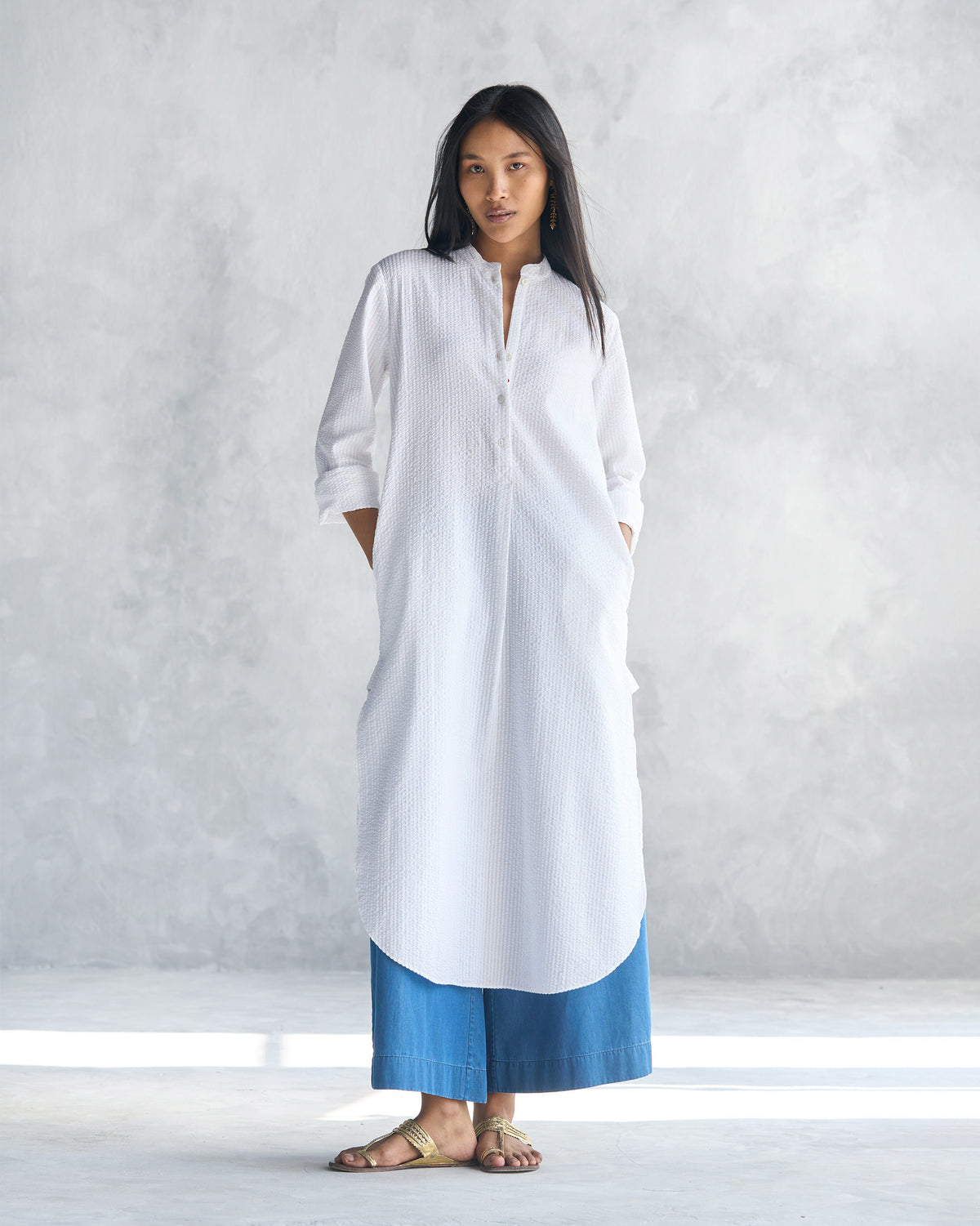 Person wearing a white seersucker long kurta with a mandarin collar.