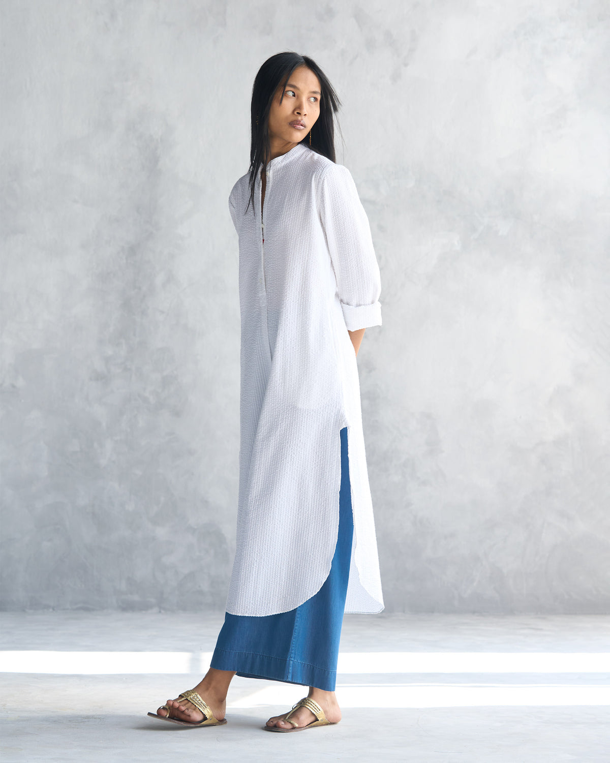 Side view of a white seersucker long kurta with a curved hem.