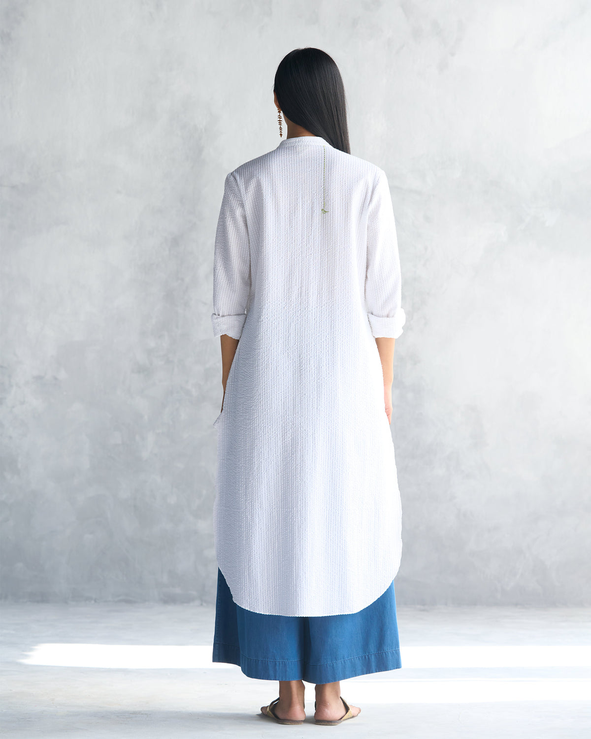 Back of a white seersucker long kurta with a curved hem.