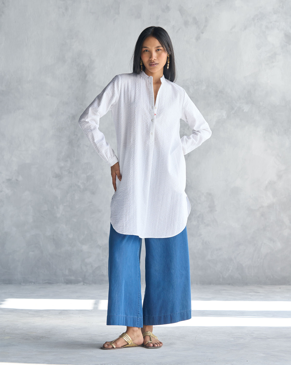 Person wearing a white seersucker mid-length kurta with a curved hem.