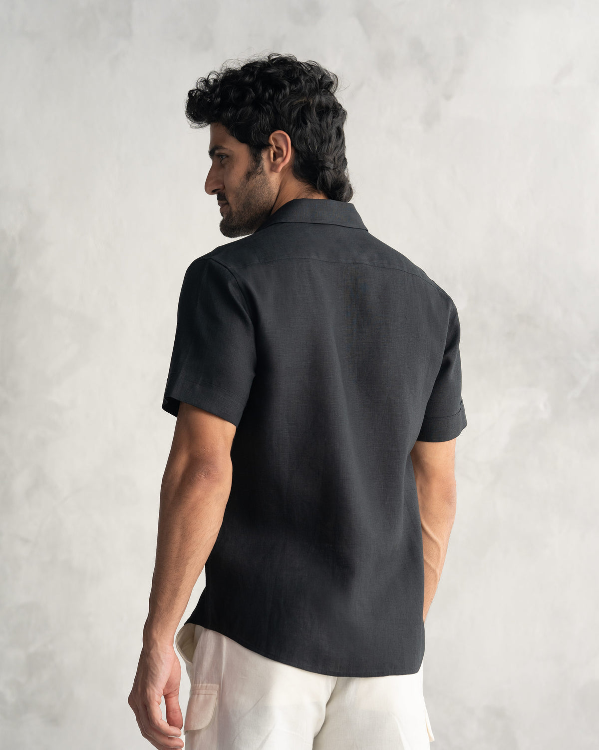 Back of a black half sleeve shirt worn by a person.