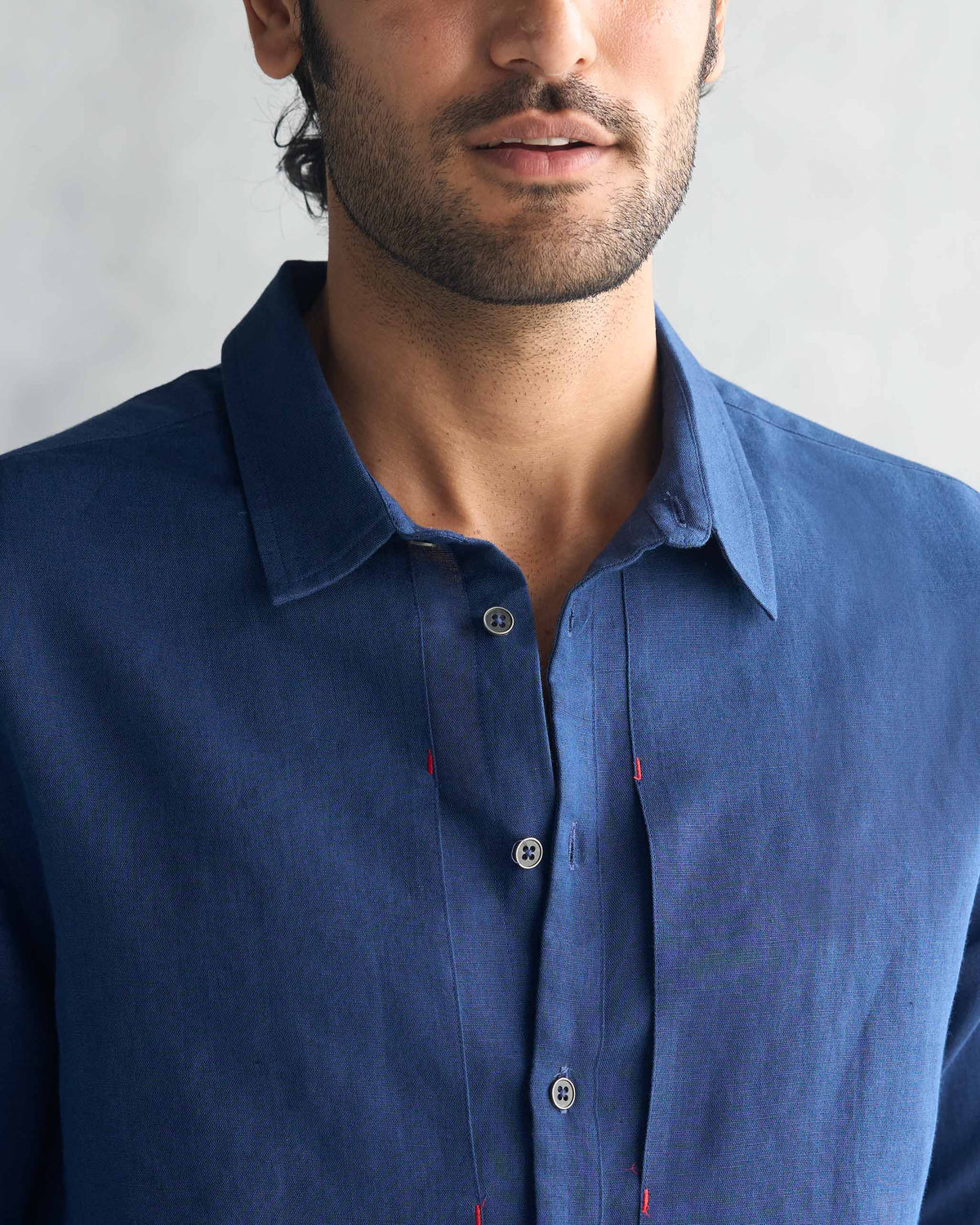 Close-up of a navy August Shirt showing the collar, placket, and red bar tacks.