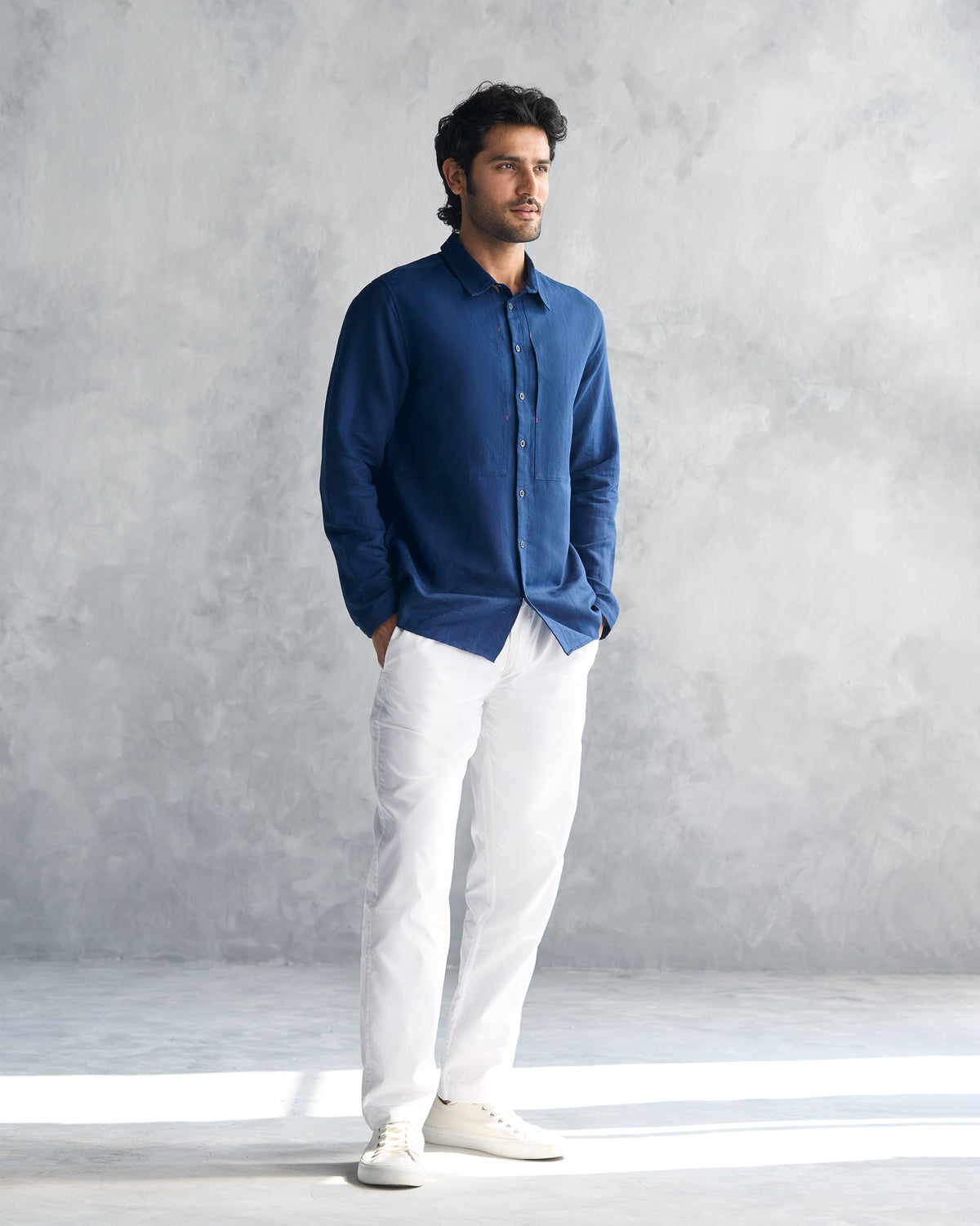 Person wearing a navy August Shirt with white trousers.