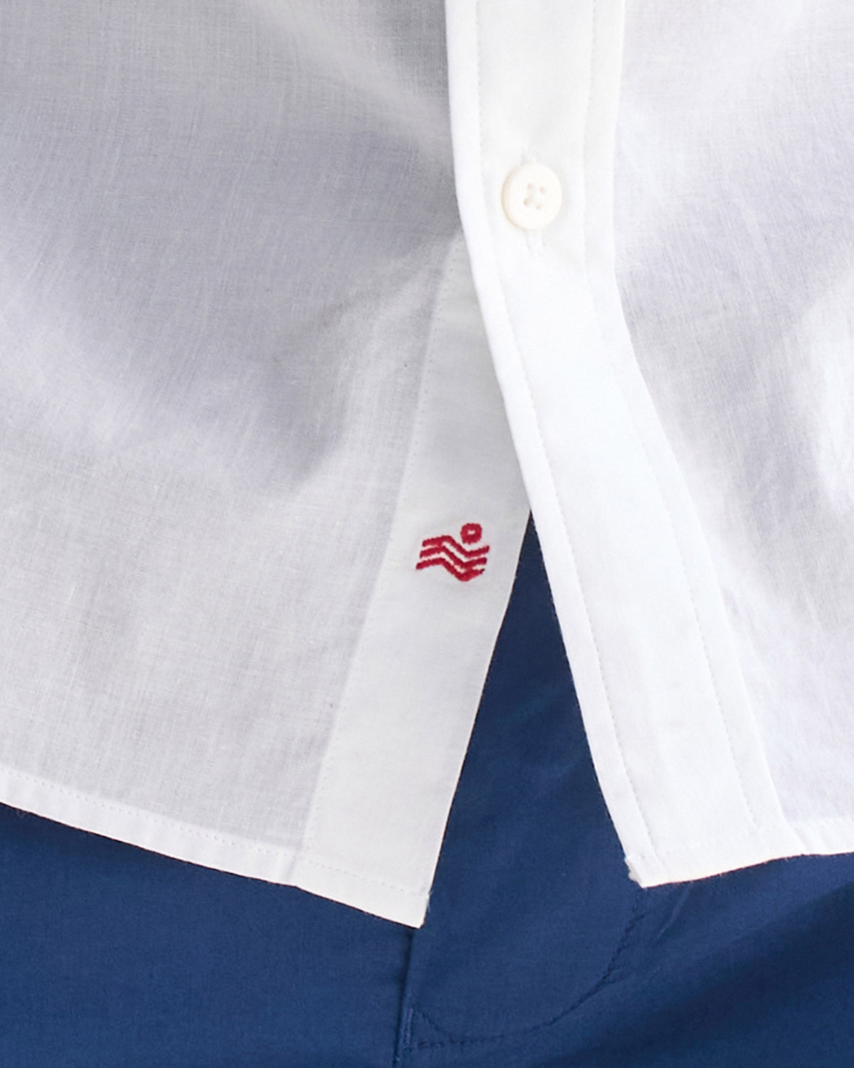 Close-up of a red logo embroidered inside the placket of a white Classic shirt.
