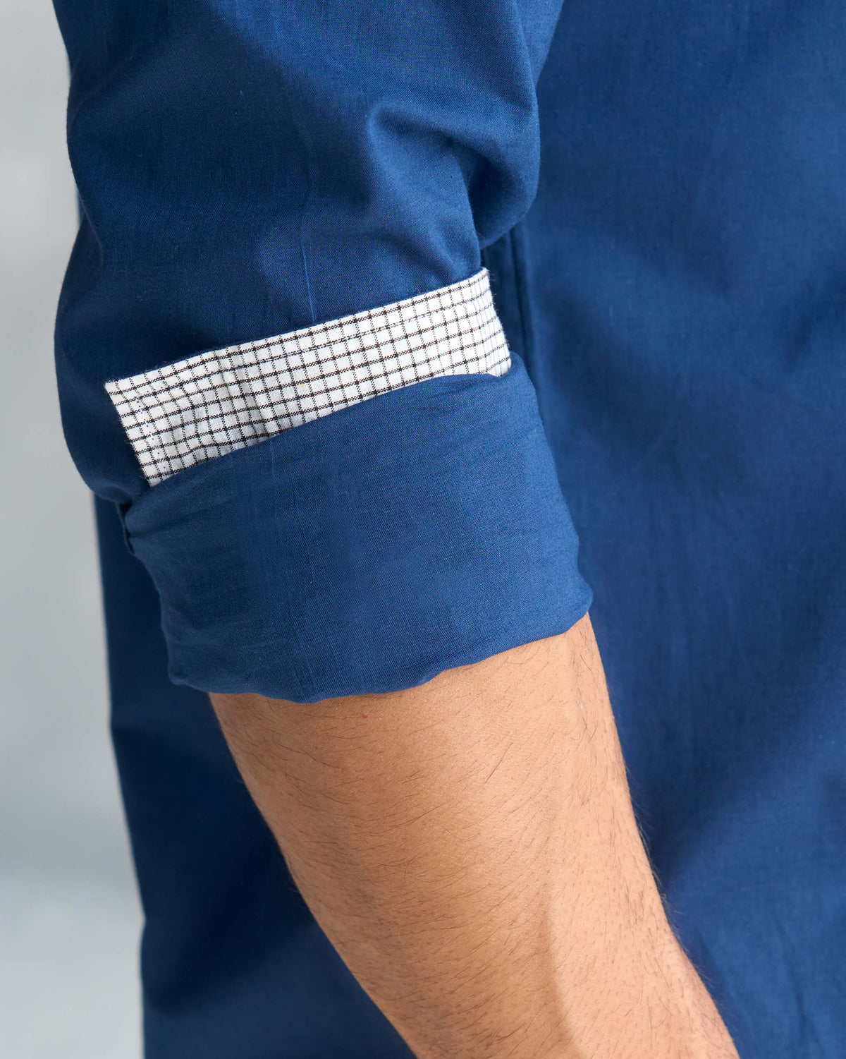 Close-up of a navy Classic Shirt sleeve rolled to show a white grid-check lining.