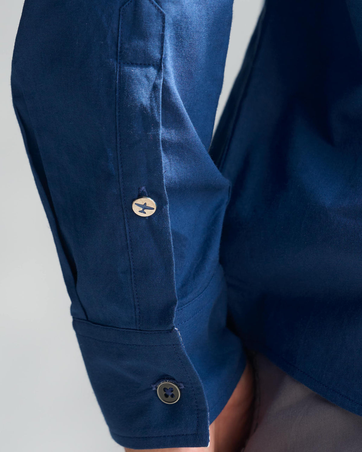 Close-up of a navy Classic Shirt cuff with an airplane button on the sleeve placket.