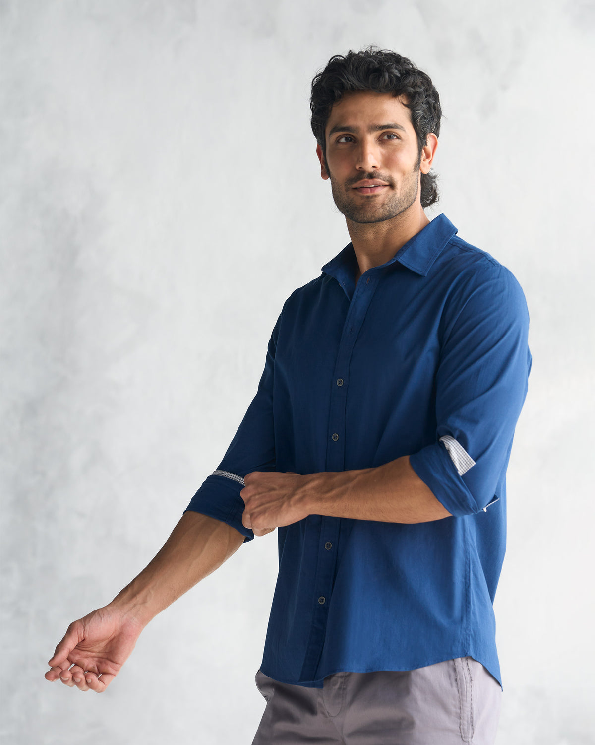 Three-quarter view of a navy Classic Shirt with sleeves rolled to show the cuff lining.