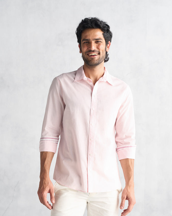 Person wearing a pink Classic Shirt with rolled sleeves and white stripe bands near the cuffs.