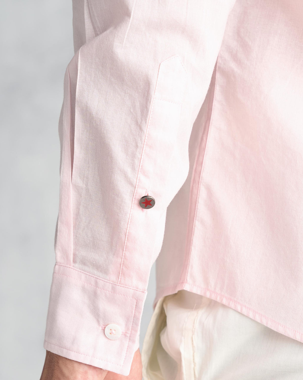 Close-up of a pink Classic Shirt cuff with a red star button on the sleeve placket.